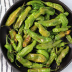 A close up picture of a black bowl with air fryer cooked shishito peppers.
