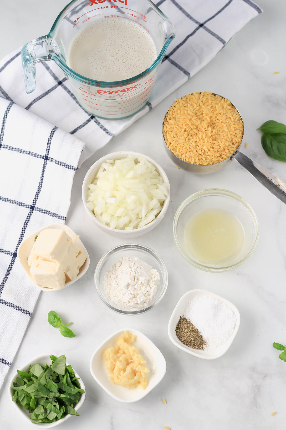 Ingredients for creamy garlic orzo pasta on a white counter.