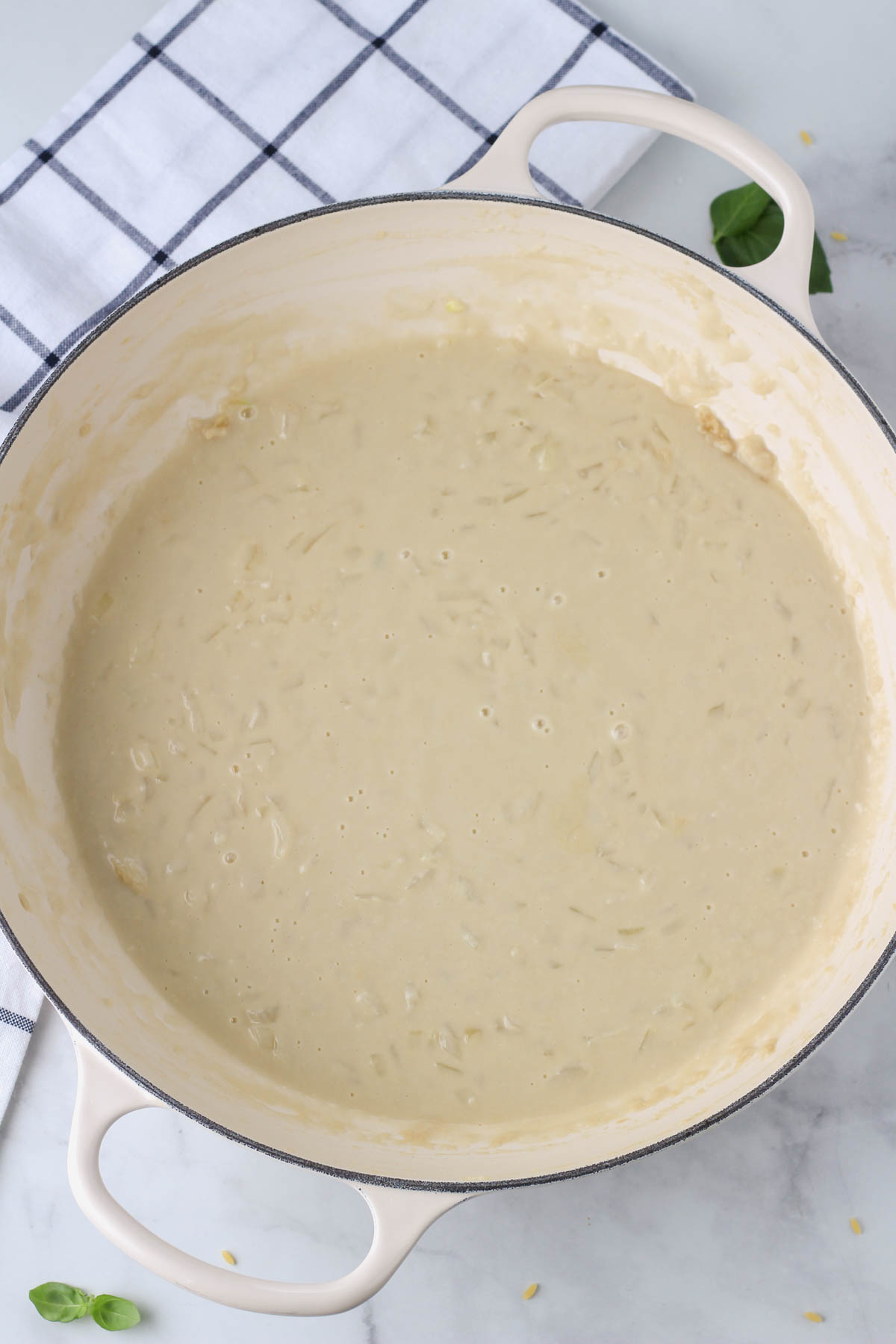 A white pan with creamy garlic sauce after the oat milk is added.