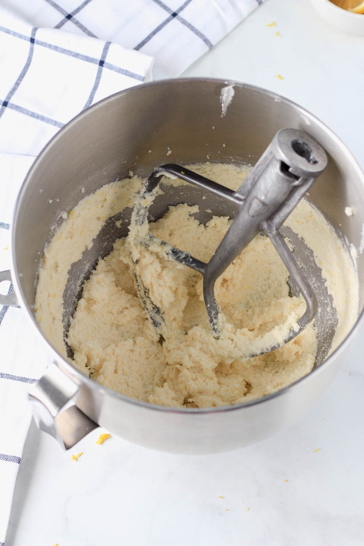 A silver mixing bowl with creamed butter and sugar.