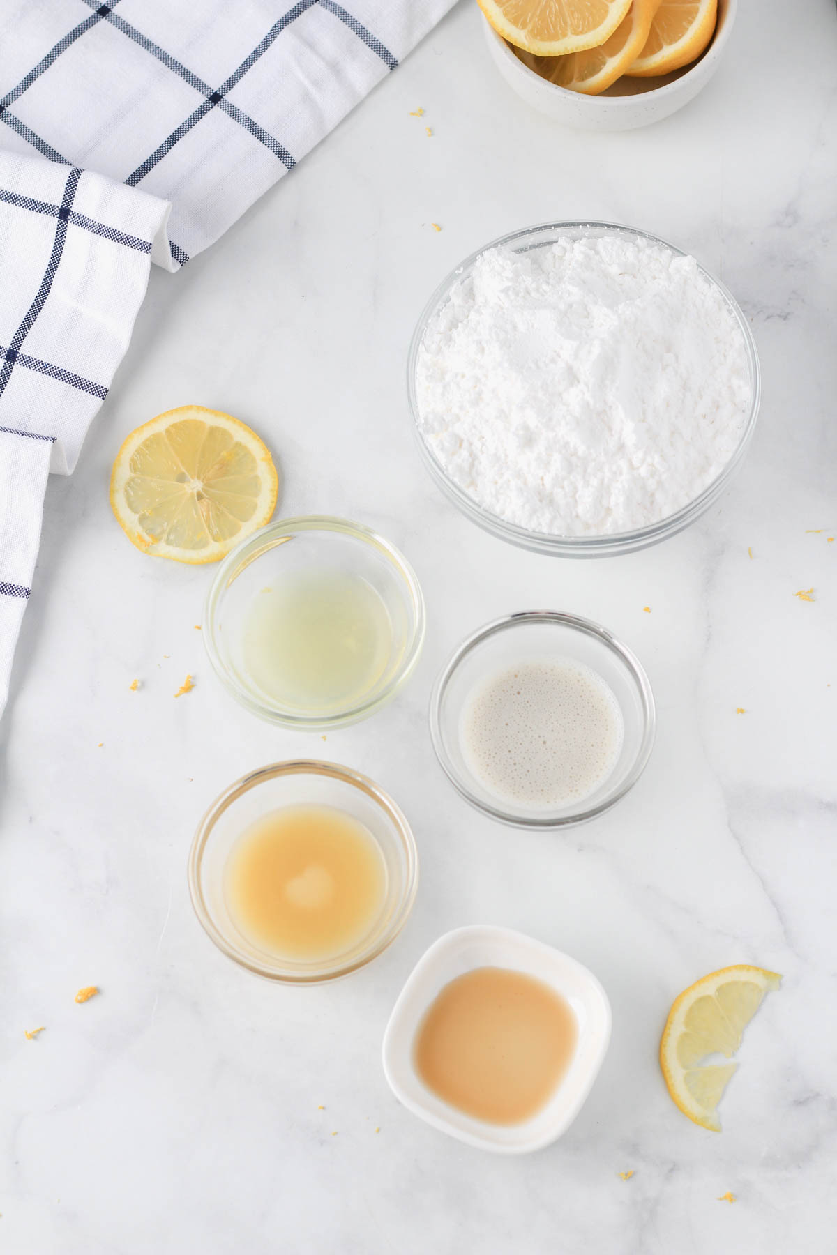 Ingredients for a lemon icing on a white counter.