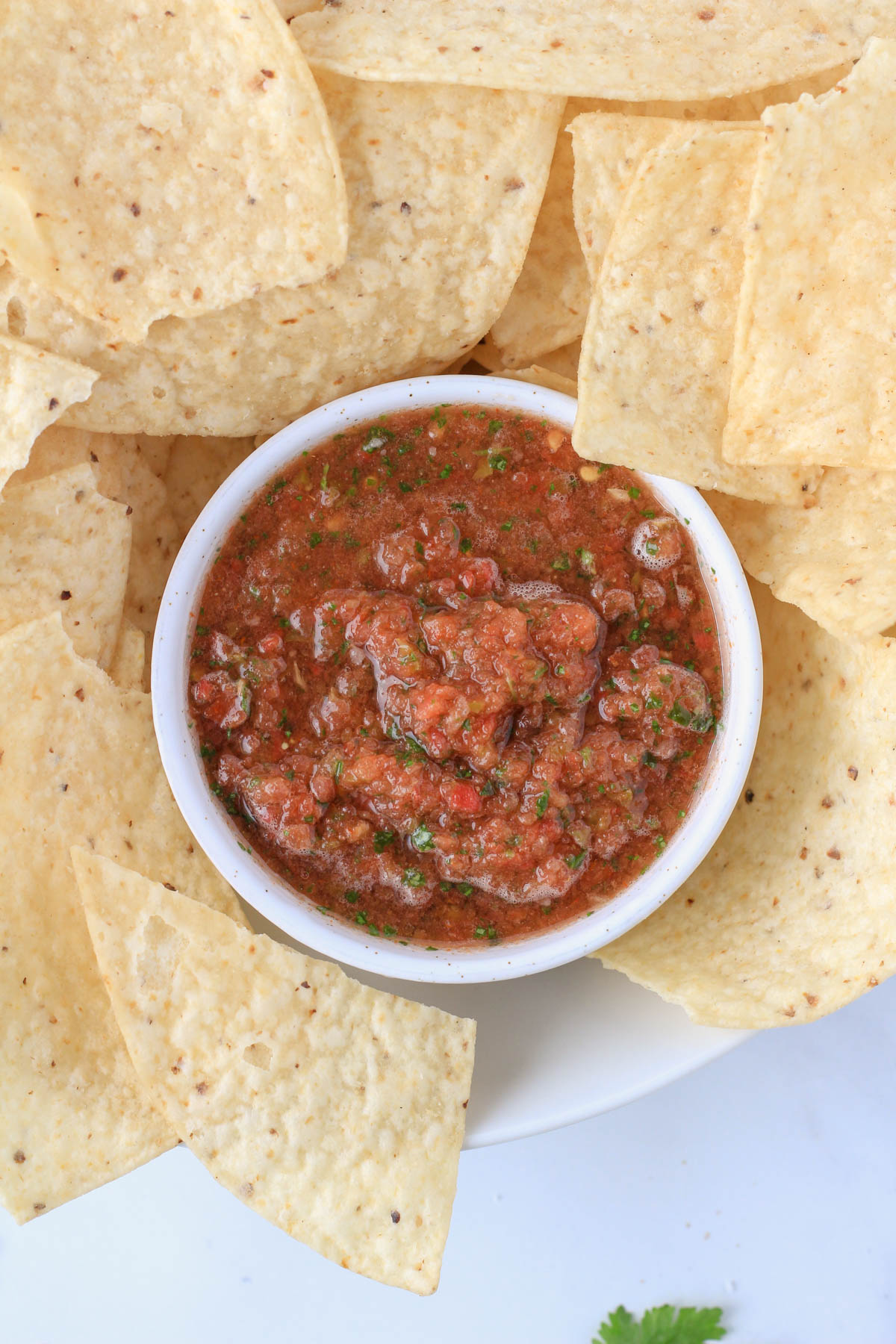 A small white bowl inside a larger white bowl with tortilla chips.