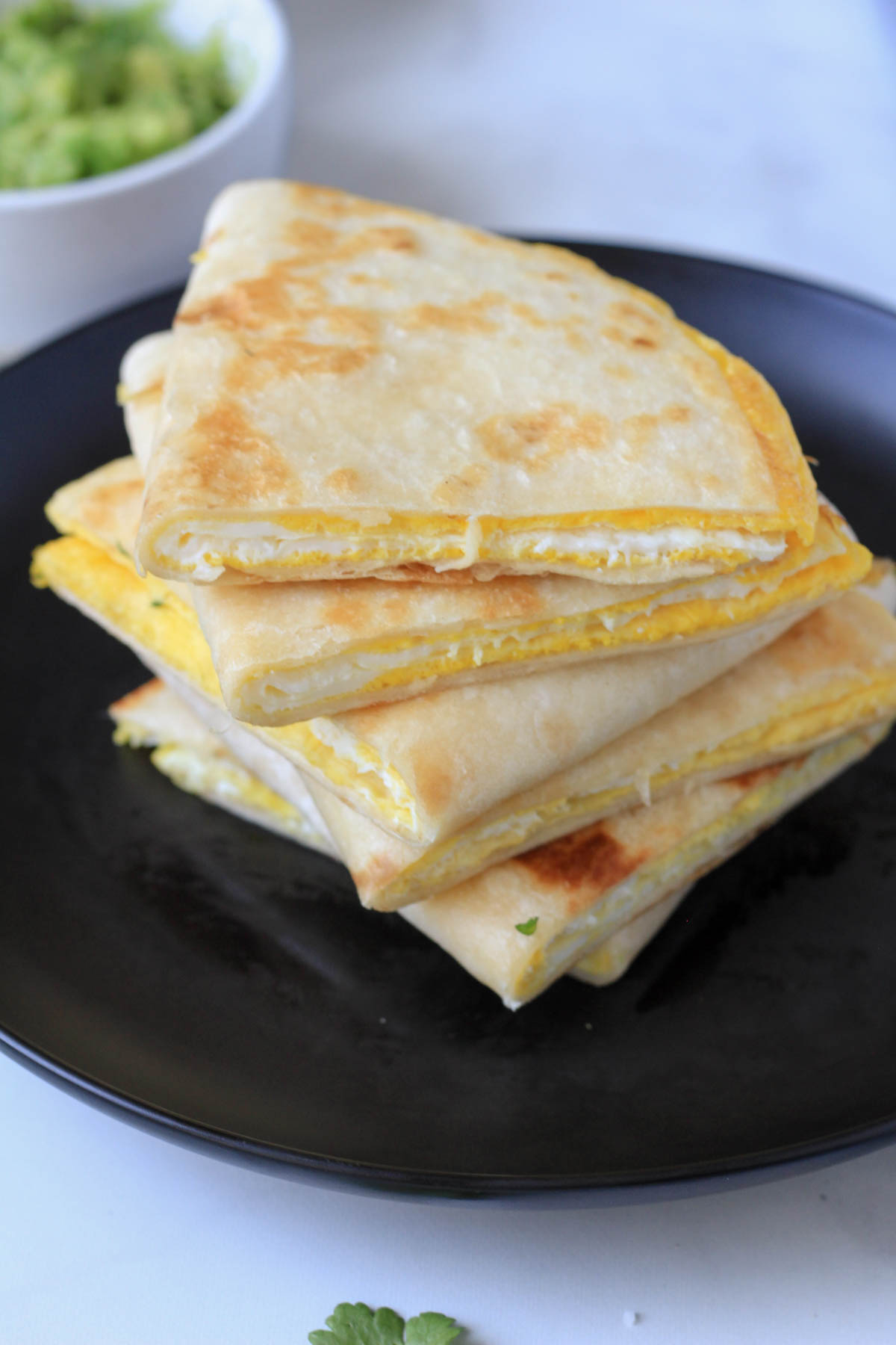 A black plate with egg-a-dillas cut in half to expose the egg center of the egg-a-dilla.