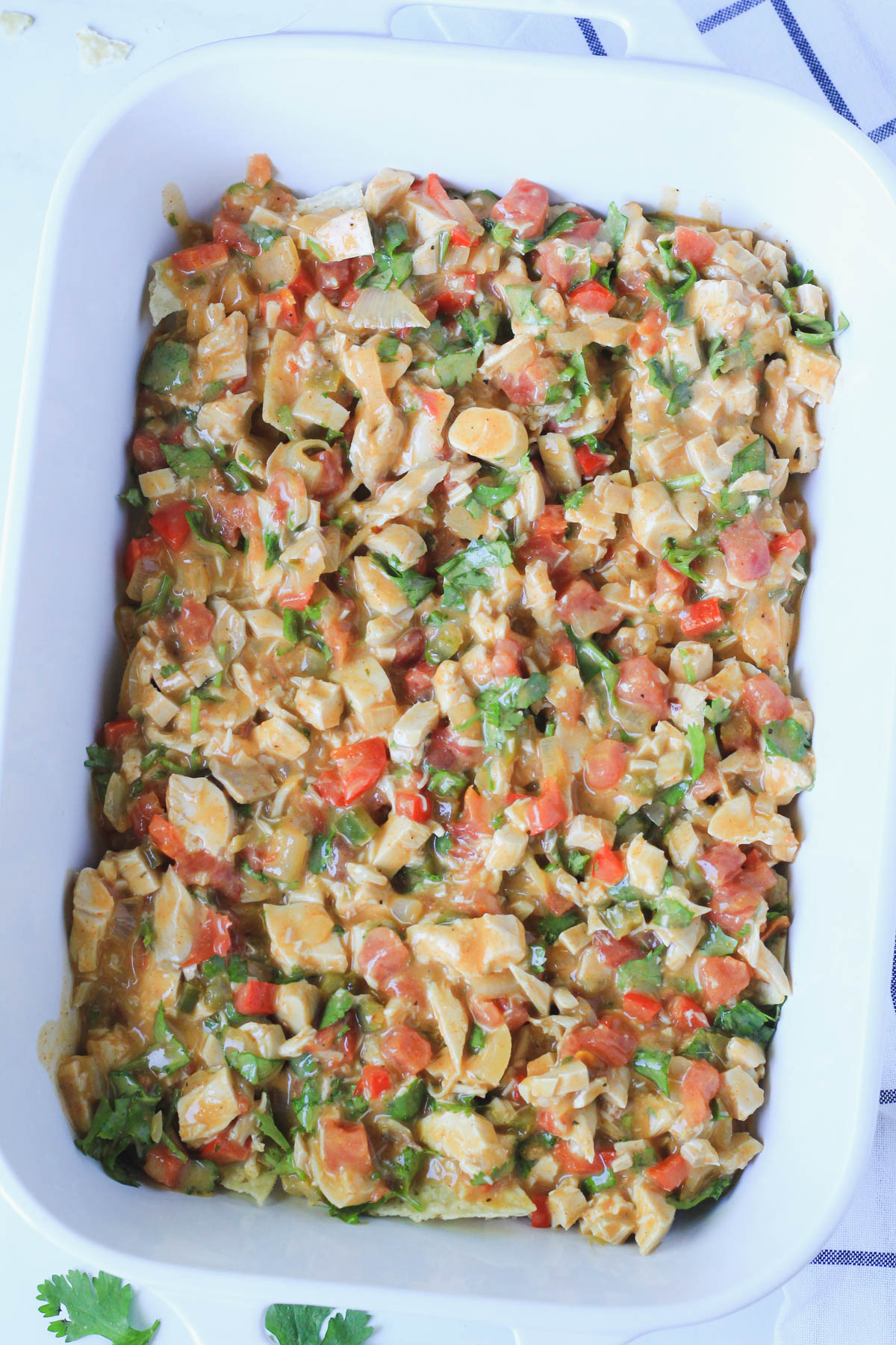 A white casserole dish with a layer of the king ranch casserole filling.