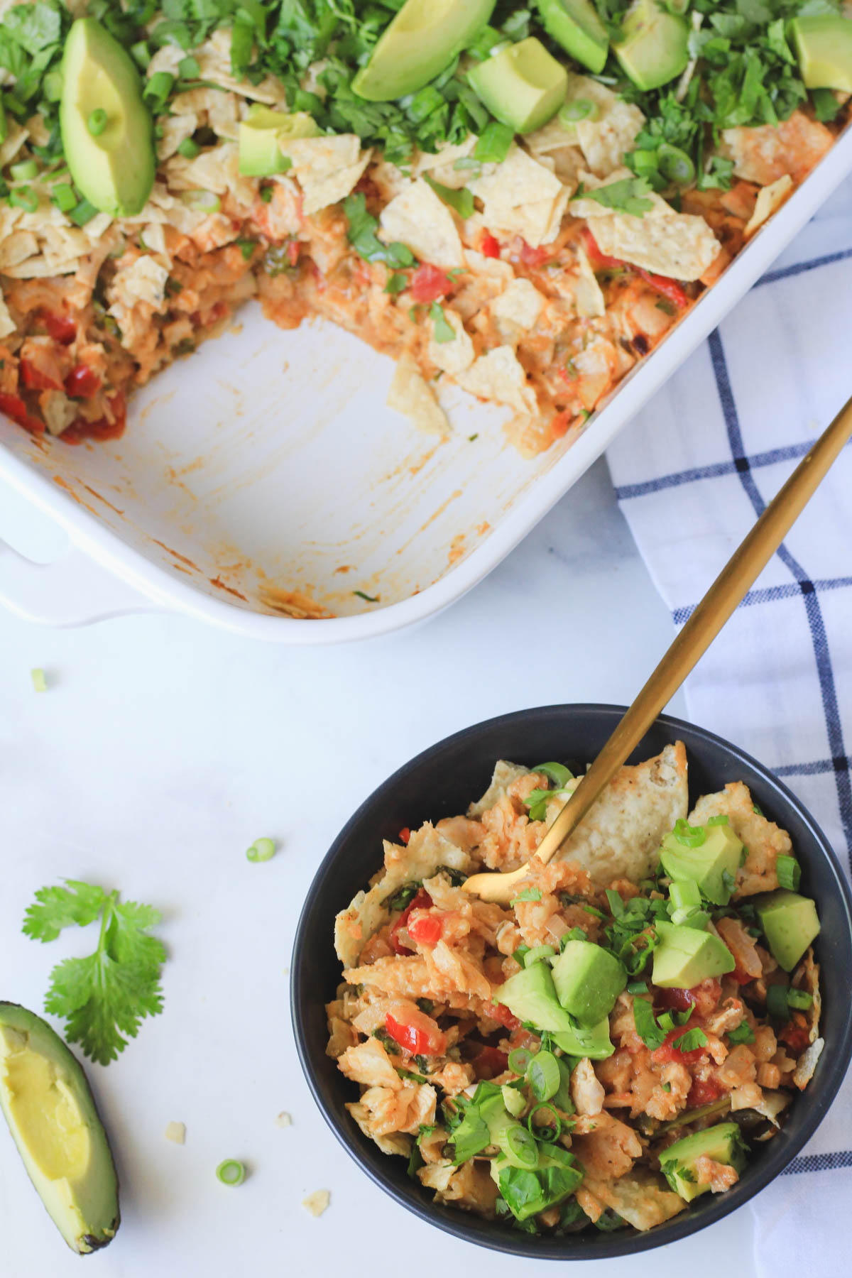 A top down picture of a white casserole pan with king ranch chicken casserole in the top left and a dark blue bowl of king ranch casserole in the bottom right.