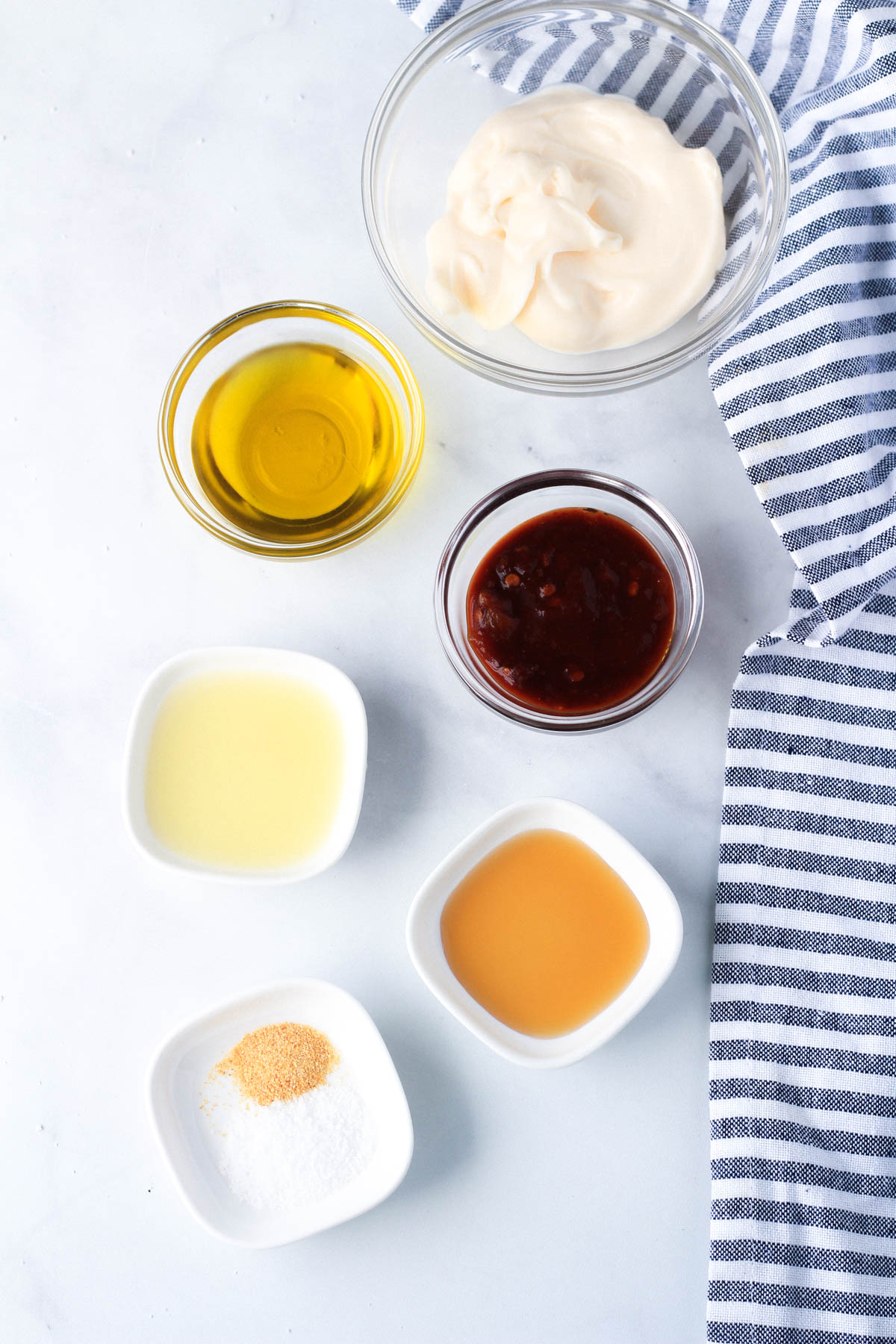 Ingredients for chipotle dressing on a white counter with a blue and white towel to the right.