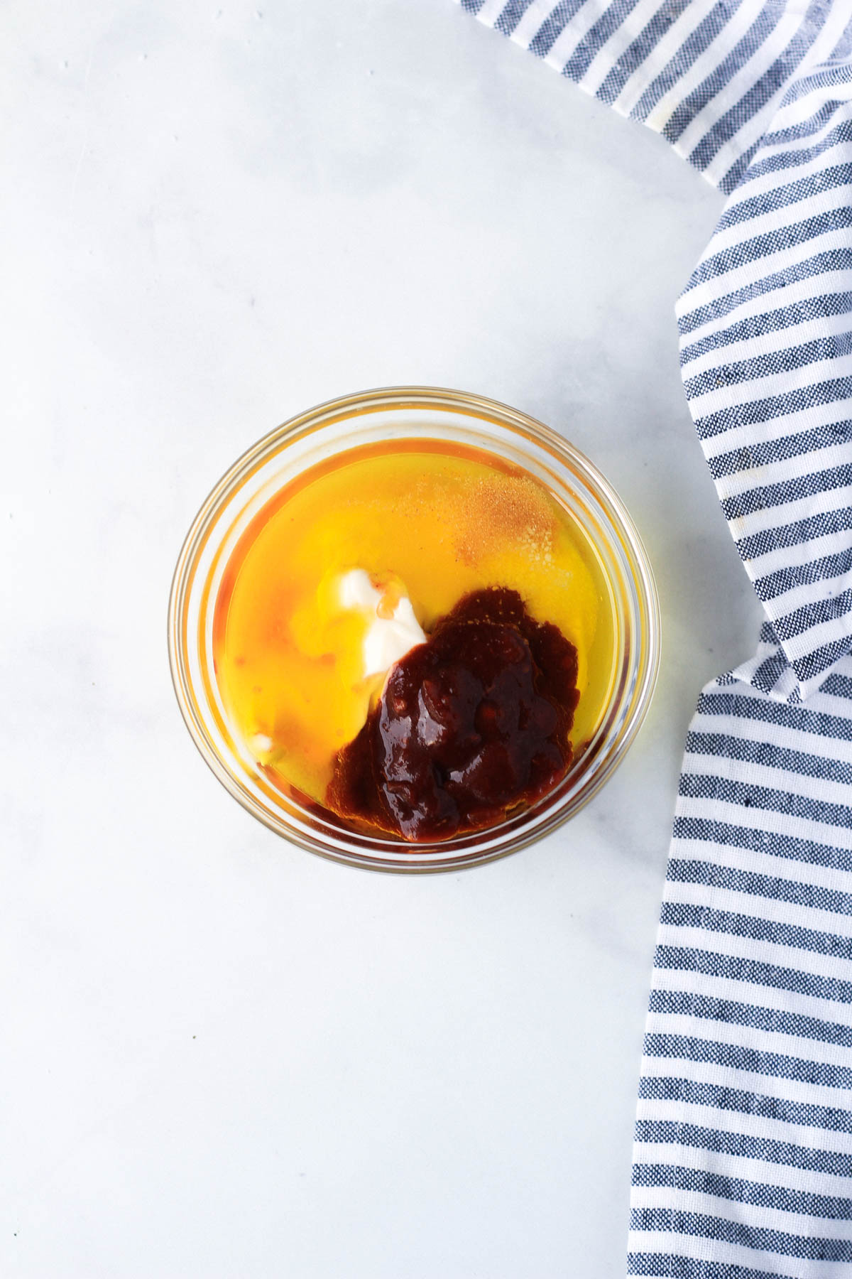 A small glass bowl with all of the ingredients for the chipotle dressing before mixing.