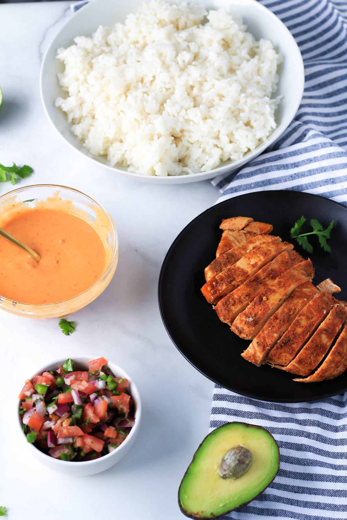 Individual ingredients for southwest chicken burrito bowls on various plates before assembling the bowls.