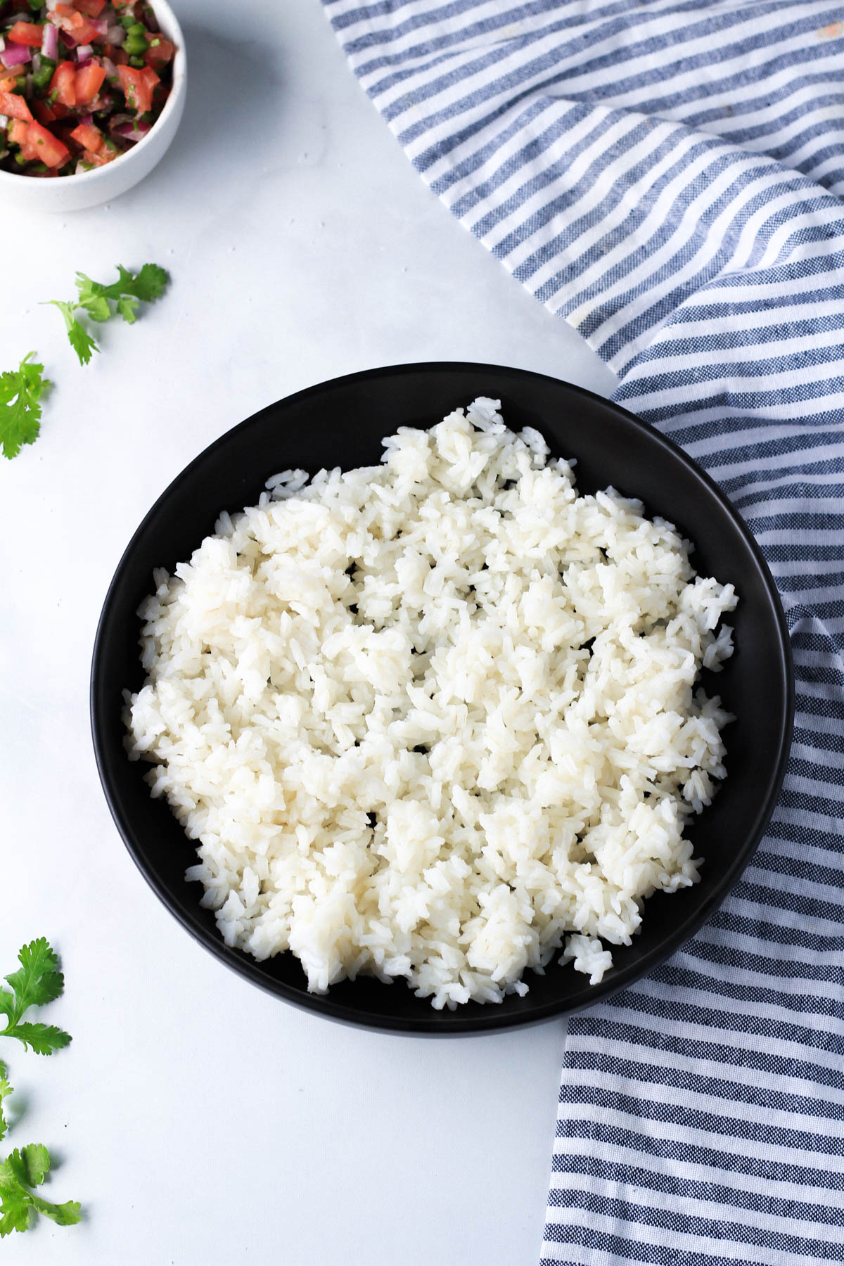 A black plate with cooked rice and a white and blue striped towel to the right.