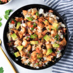 A close up of southwest chicken burrito bowl drizzled with chipotle dressing in a black bowl.