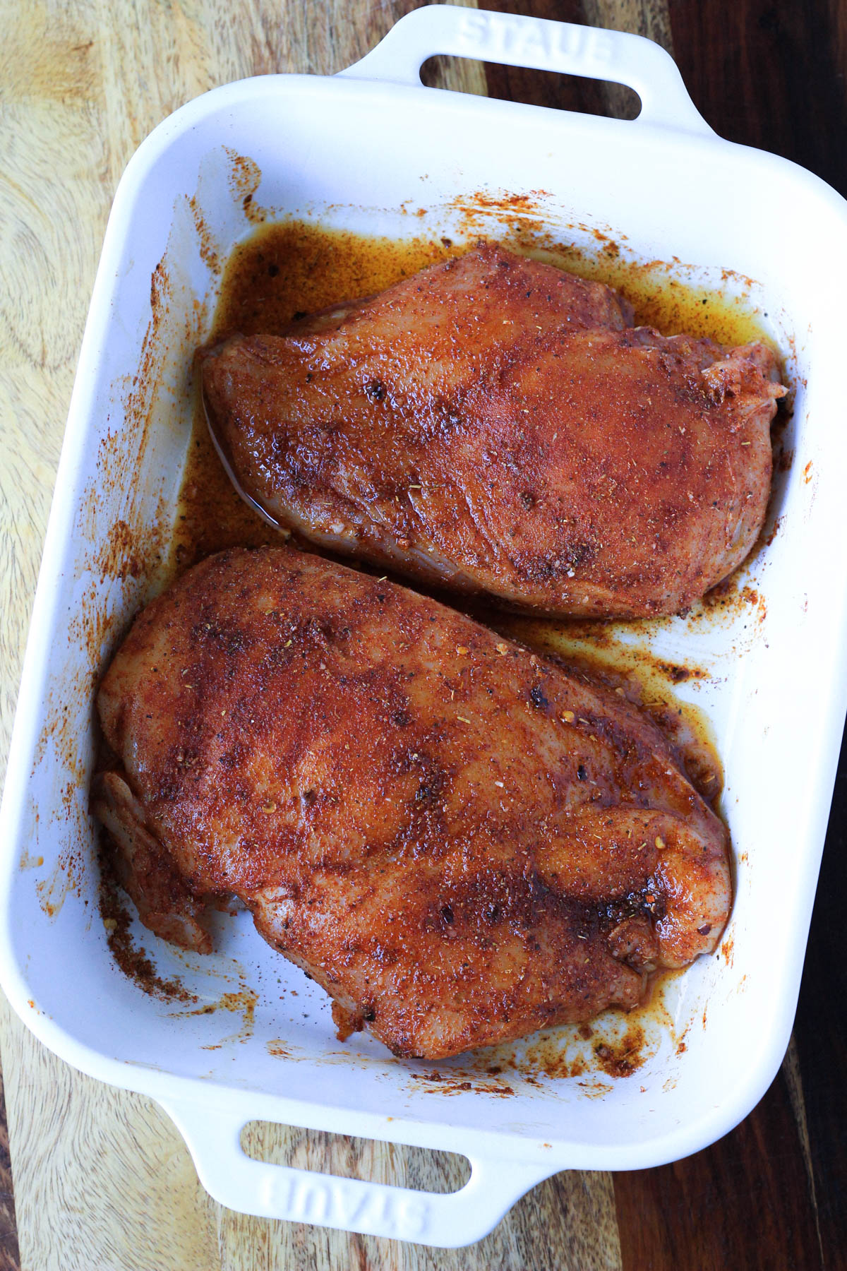 A white baking dish with southwest chicken breasts before baking.