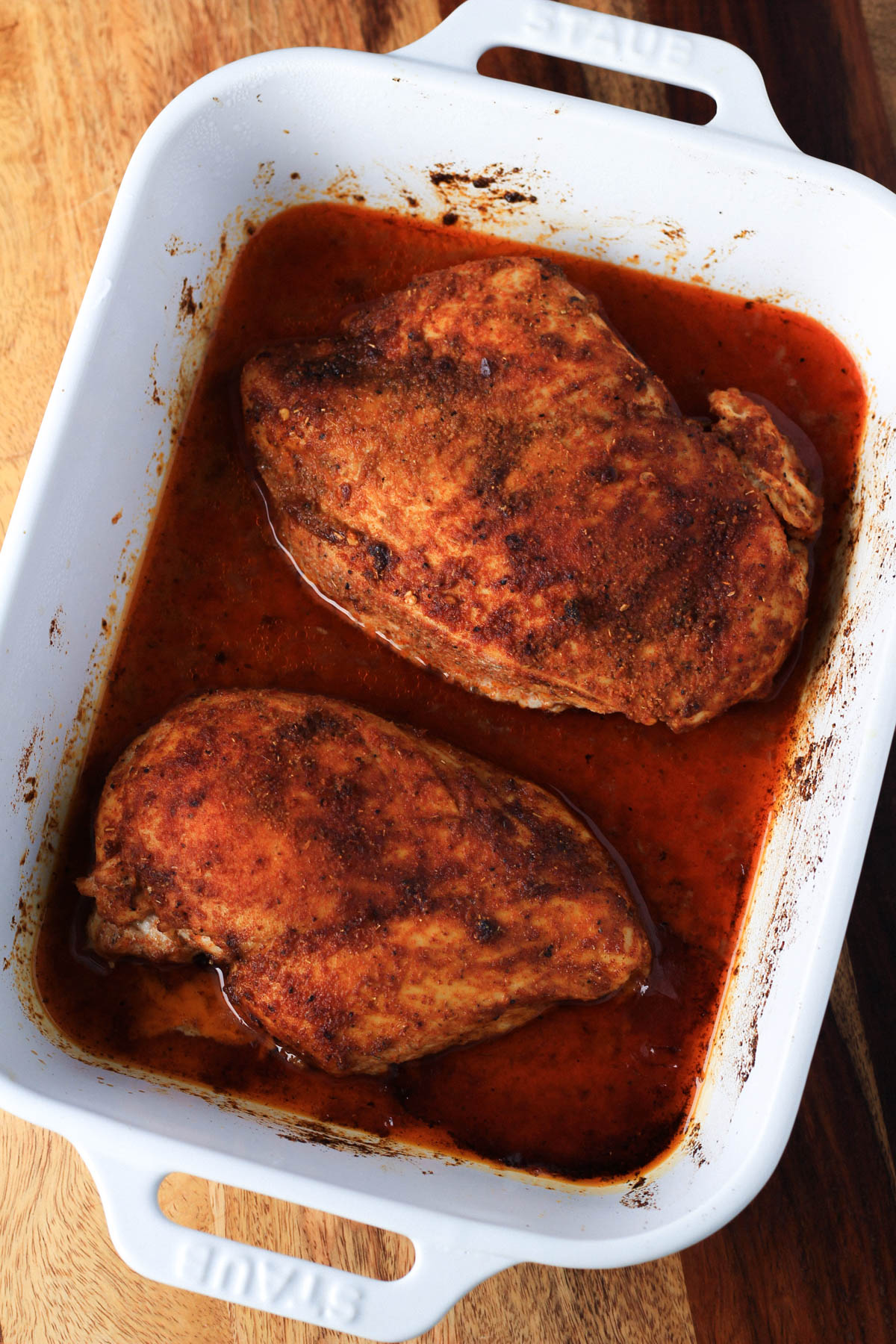A white baking dish with two southwest seasoned chicken breasts after baking. 