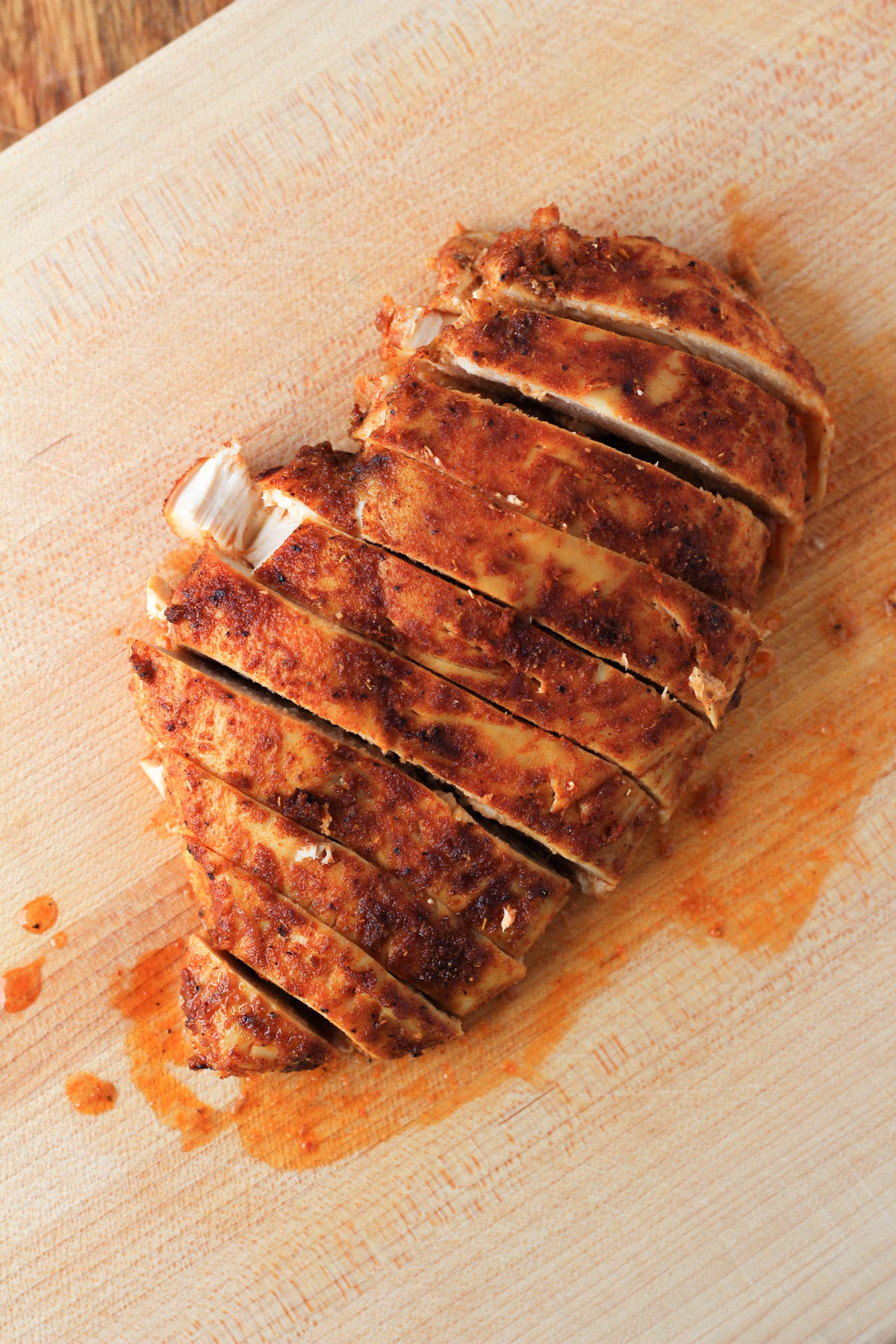 A wooden cutting board with one chicken breast cut into strips.