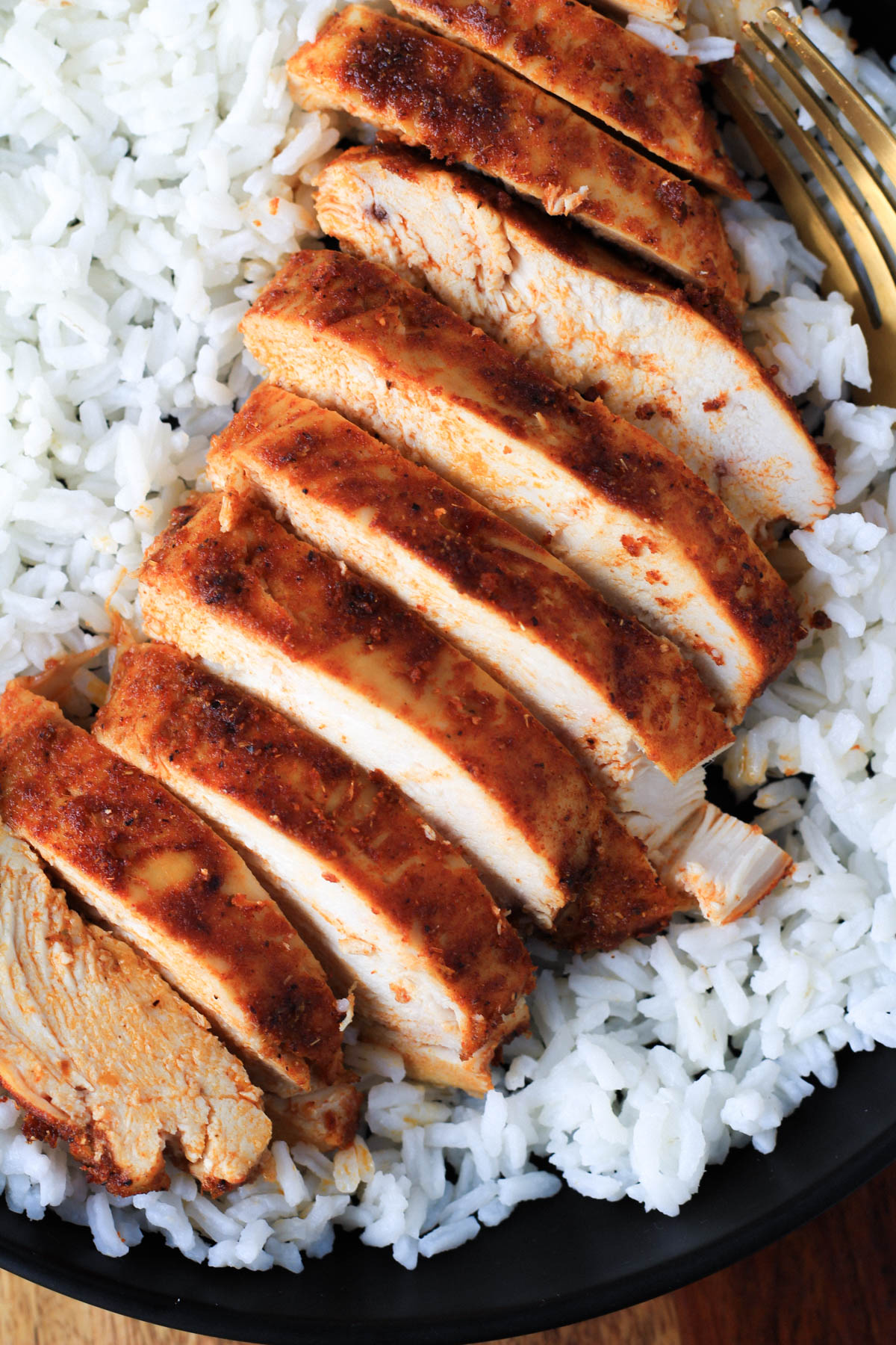 A close up of sliced southwest chicken on a bed of rice.