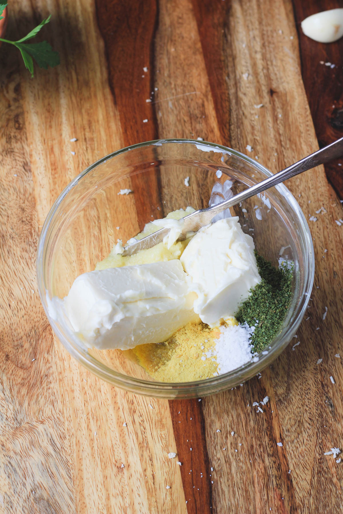 A small glass bowl with the ingredients for the garlic butter before mixing.