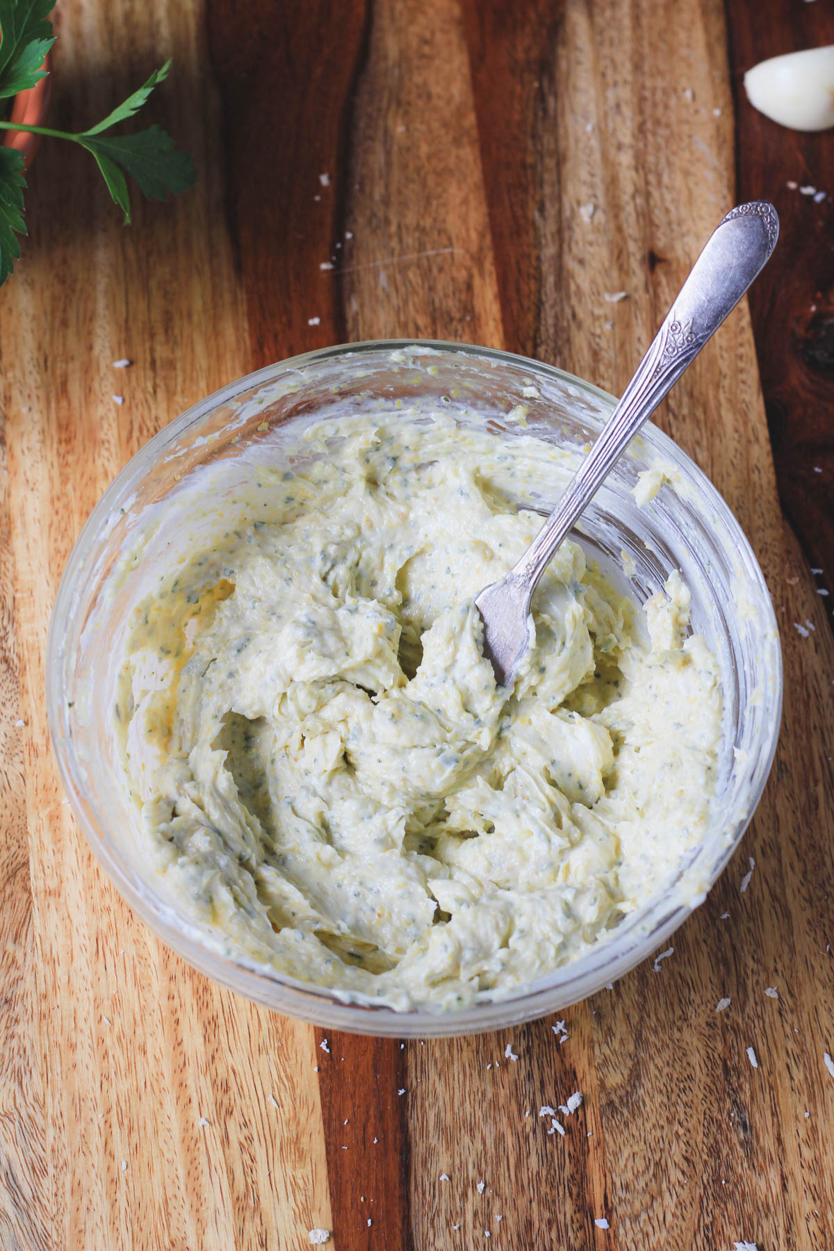 A small glass bowl with a butter knife and the ingredients for garlic butter mixed together.