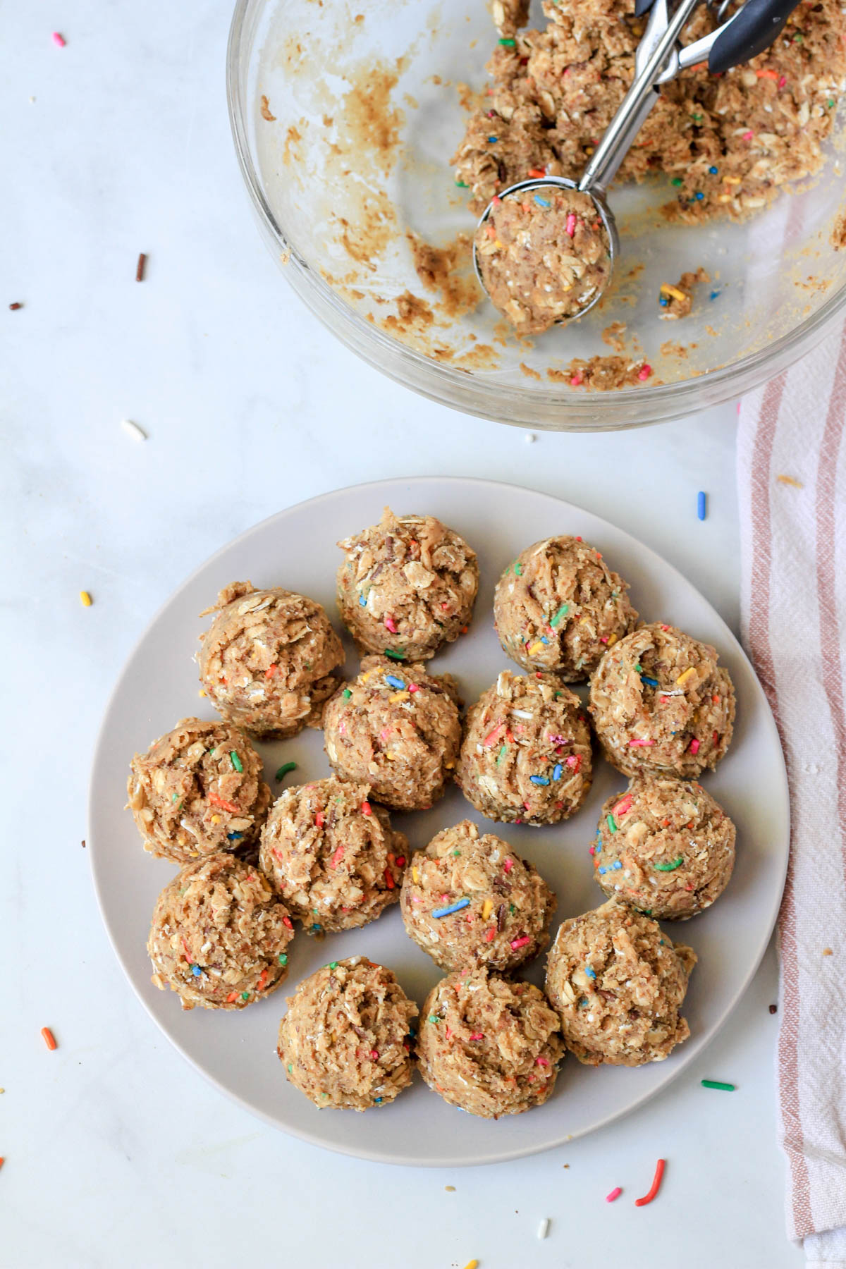 A small white plate with cake batter lactation bites after being scooped from the bowl.