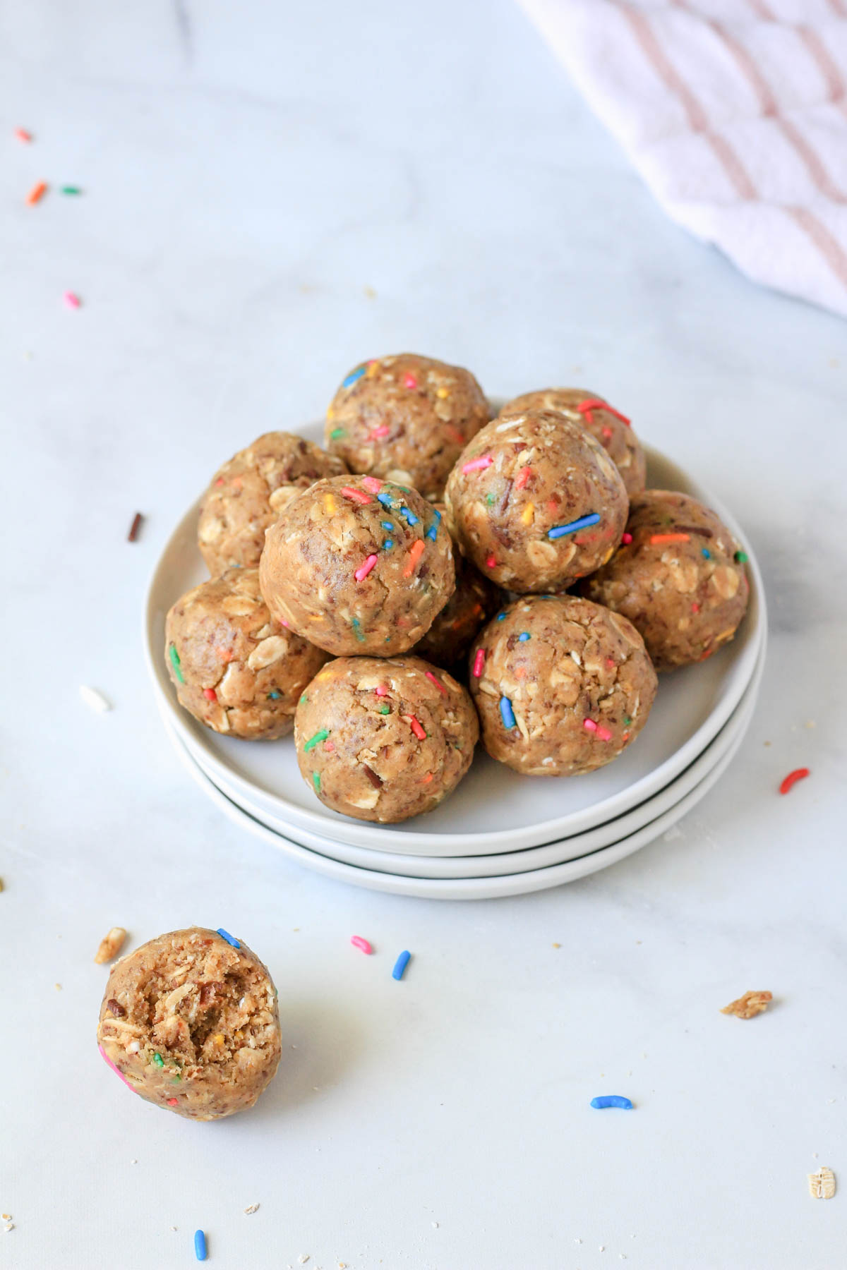 A small pile of lactation bites on a stack of plates with one lactation bite on the counter with a bite taken out.
