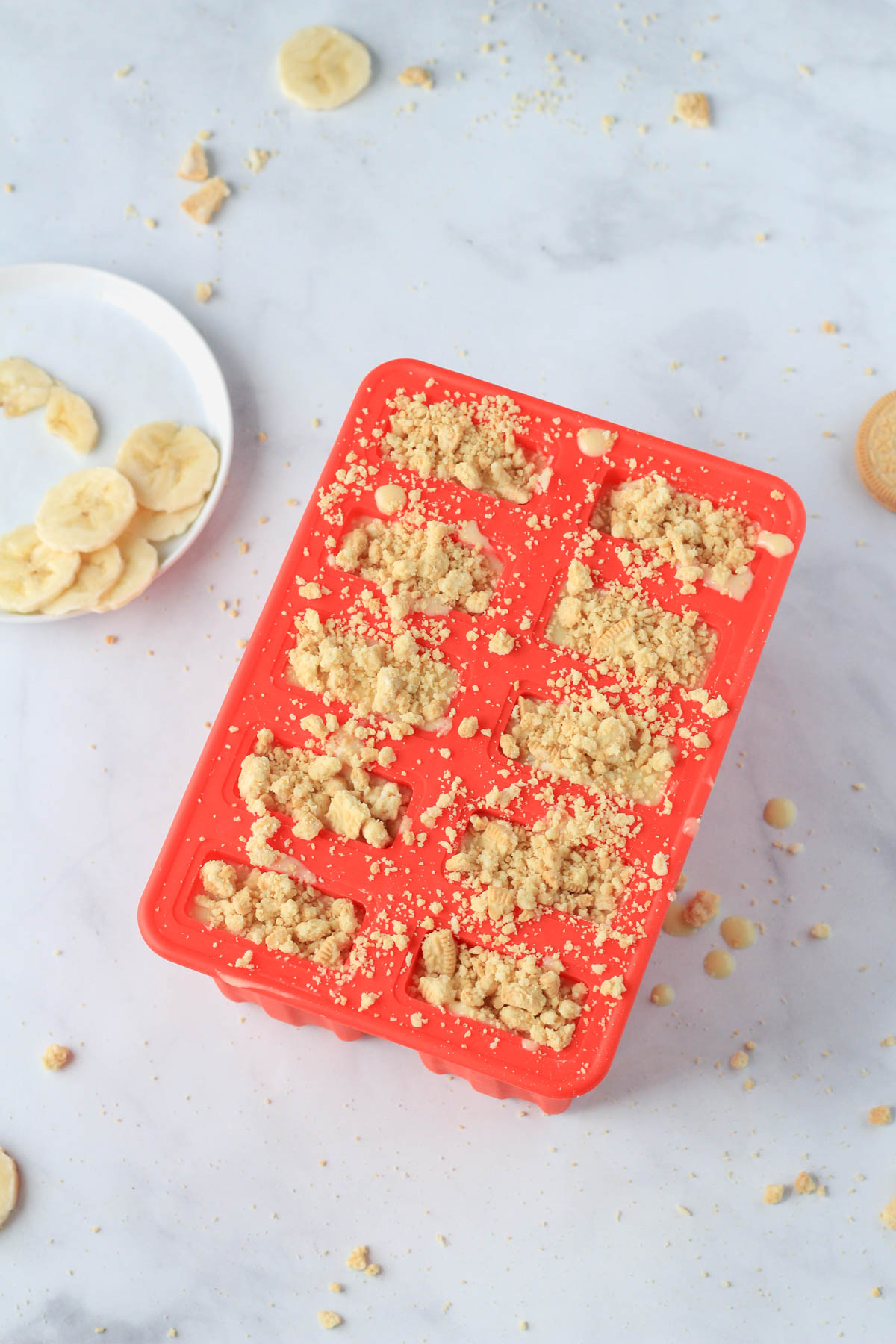 Banana pudding popsicles topped with crushed golden Oreo before freezing.