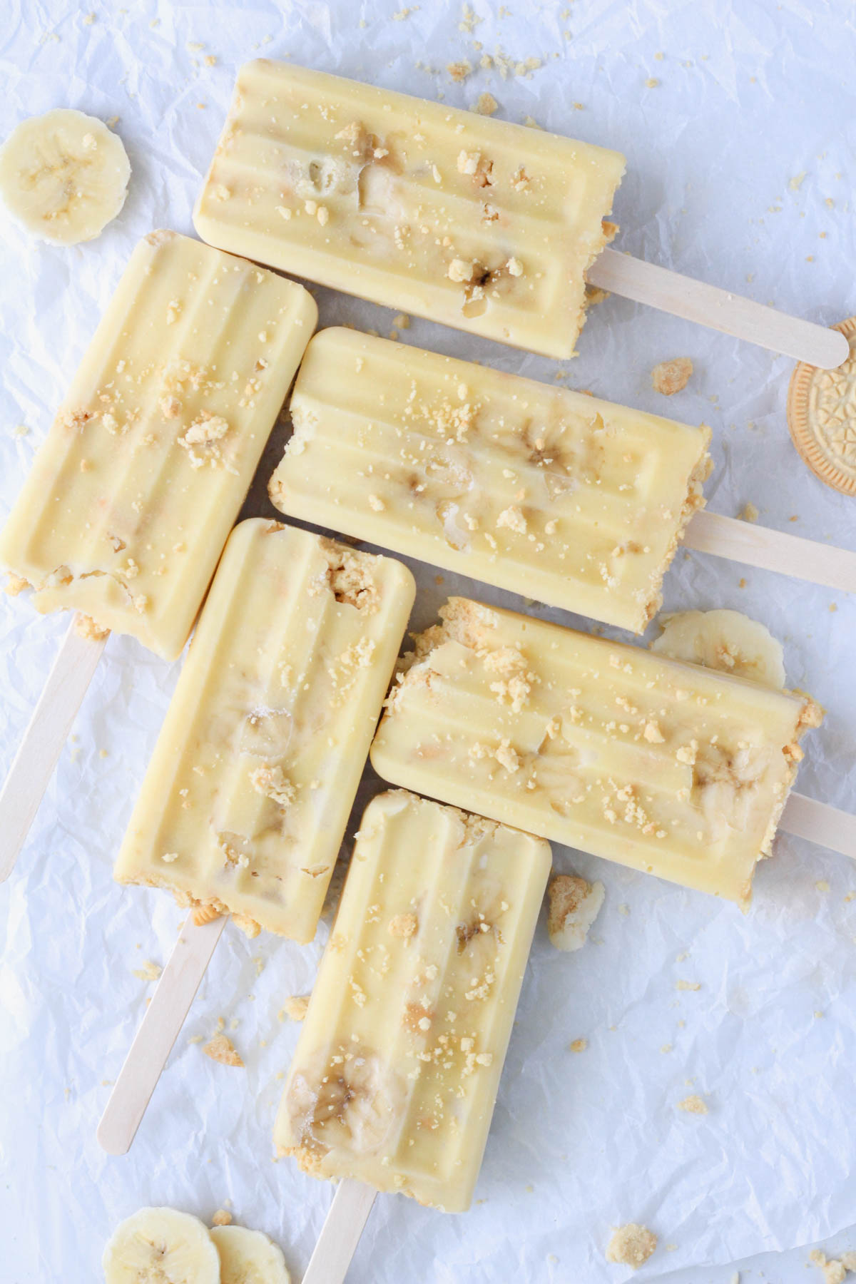 A parchment paper topped with six dairy-free banana pudding popsicles.