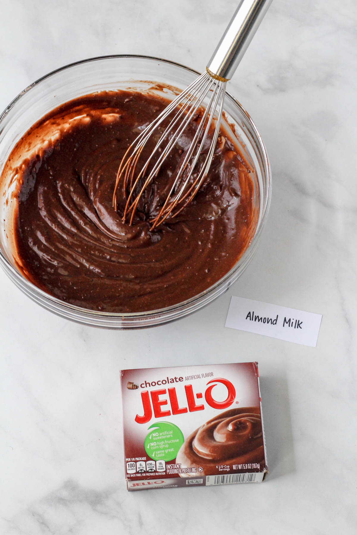 A glass bowl with chocolate jell-o pudding after mixing the almond milk in.
