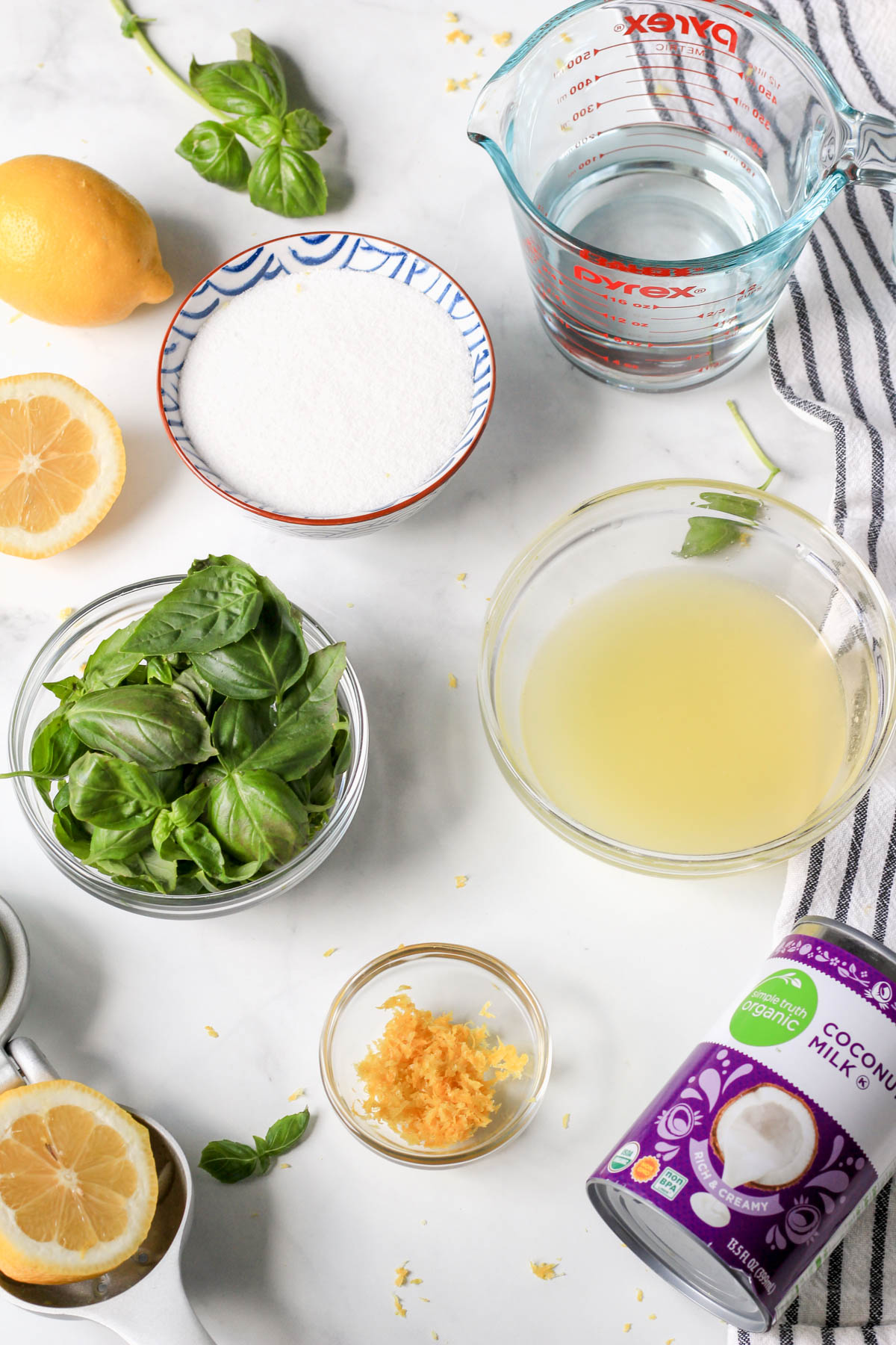 Ingredients for lemon basil popsicles on a white counter.