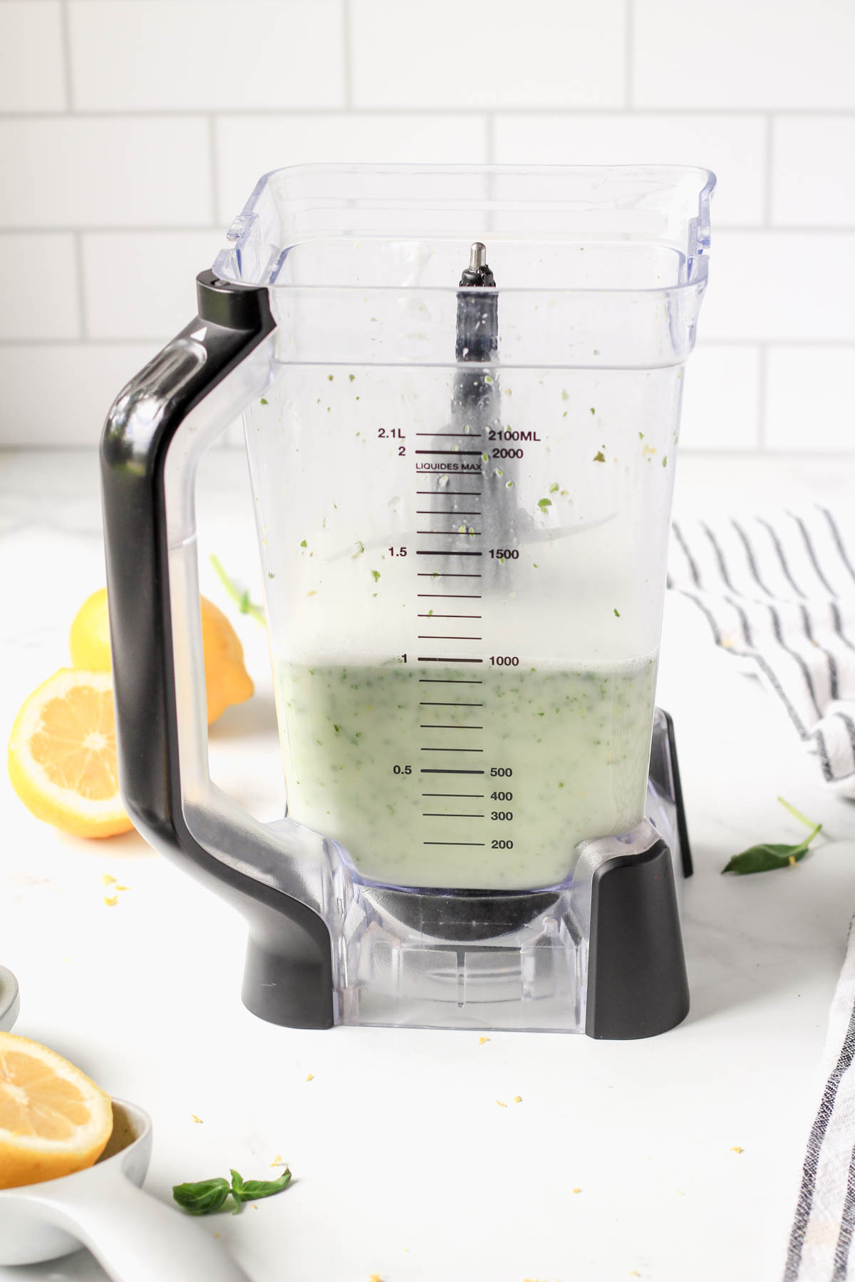 A blender pitcher with lemon basil popsicle filling after blending.
