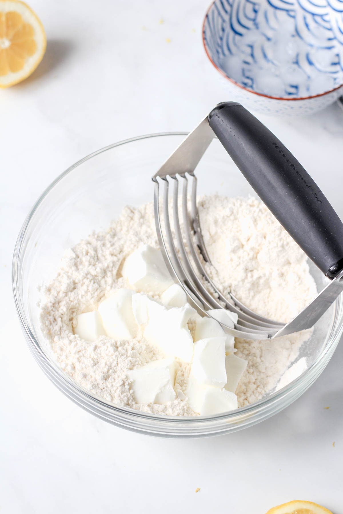A glass mixing bowl with flour and crisco being cut together with a pastry blender.