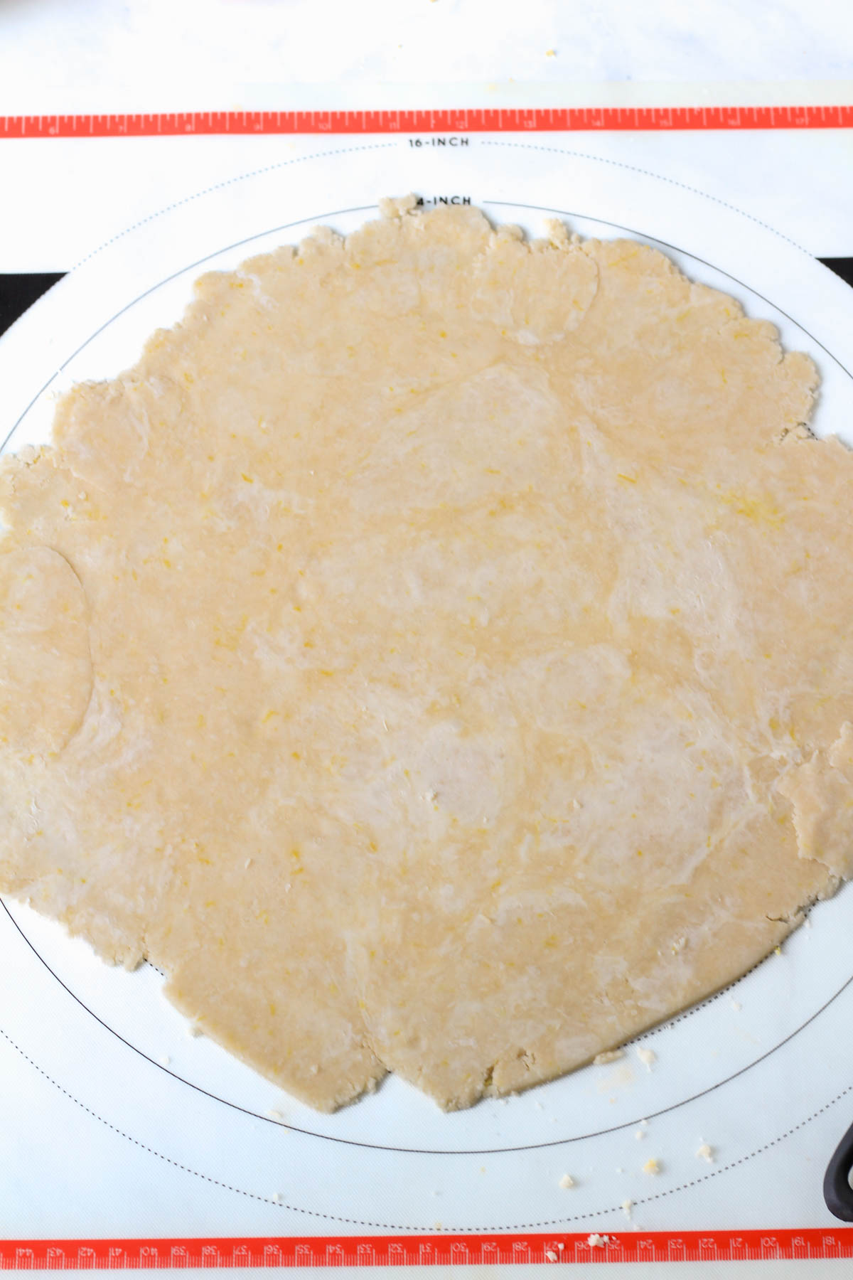 A large pastry mat with a rolled out lemon pie dough.