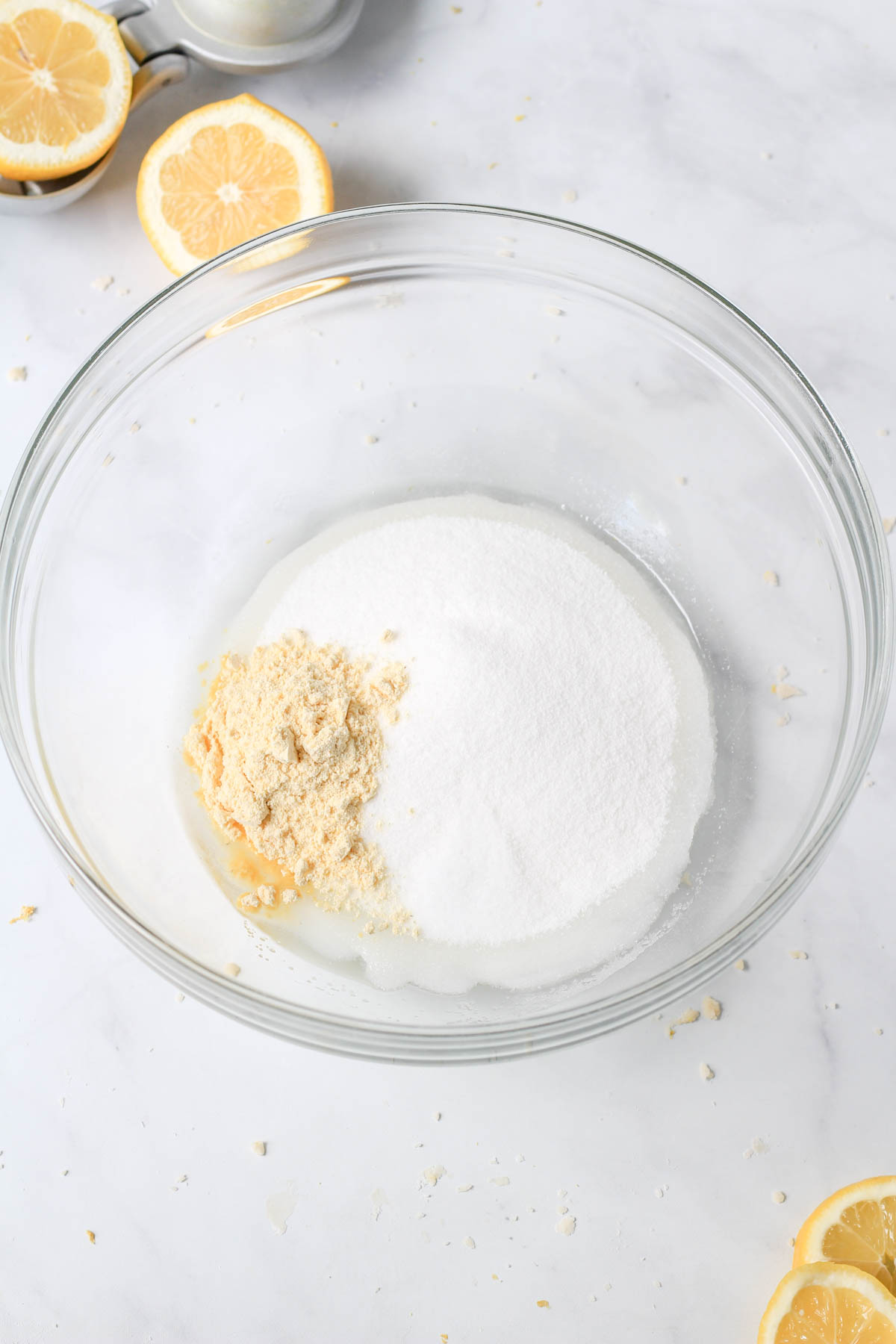 A glass mixing bowl with sugar, salt, cornmeal, and melted coconut oil.