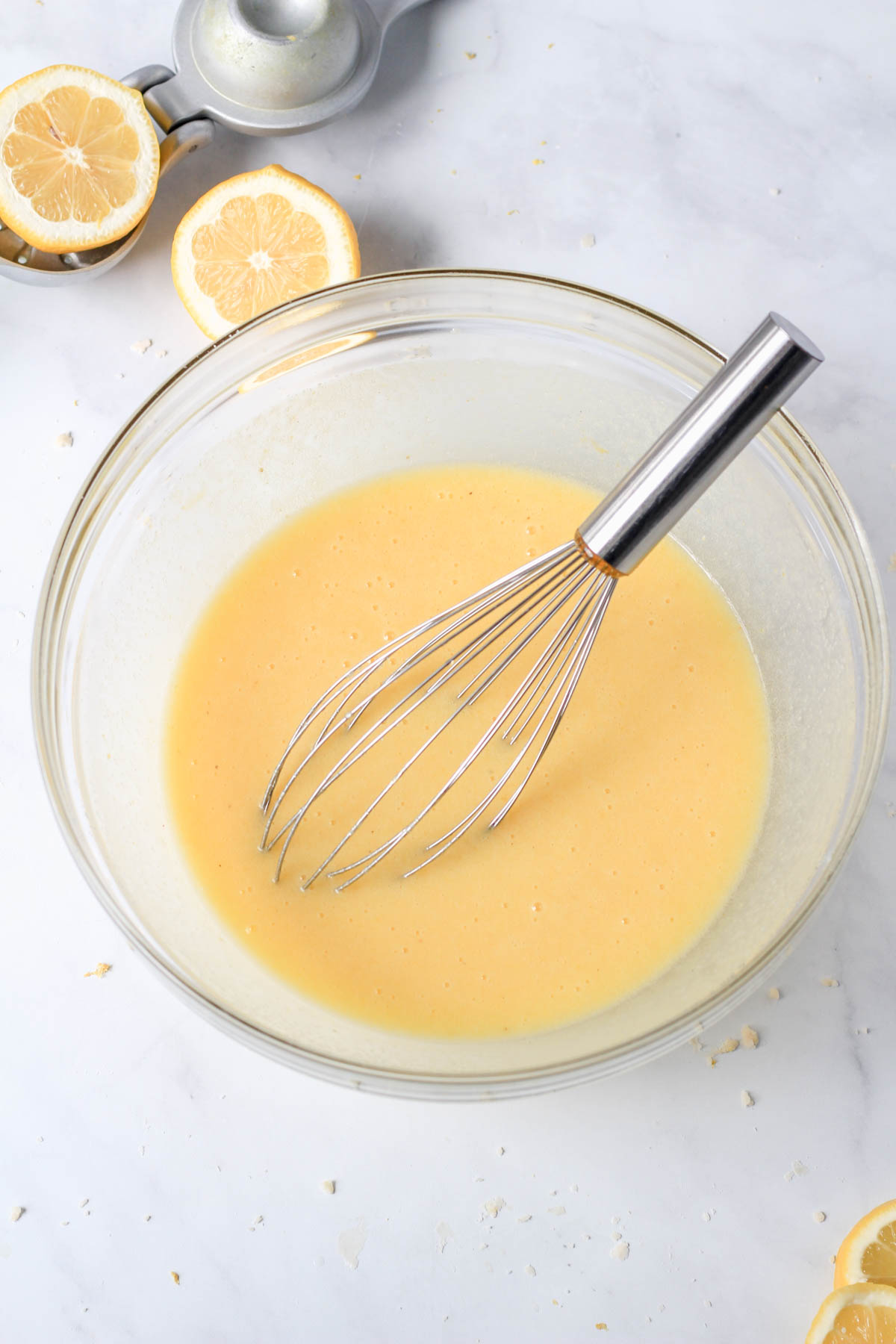 A glass mixing bowl with a whisk and the lemon chess pie filling.
