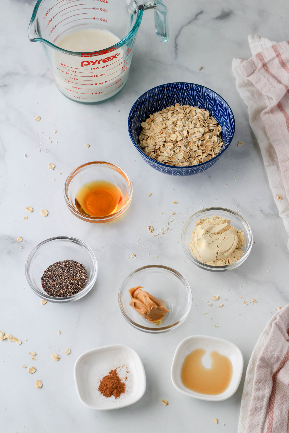 Ingredients for vegan vanilla peanut butter overnight oats on a white counter.