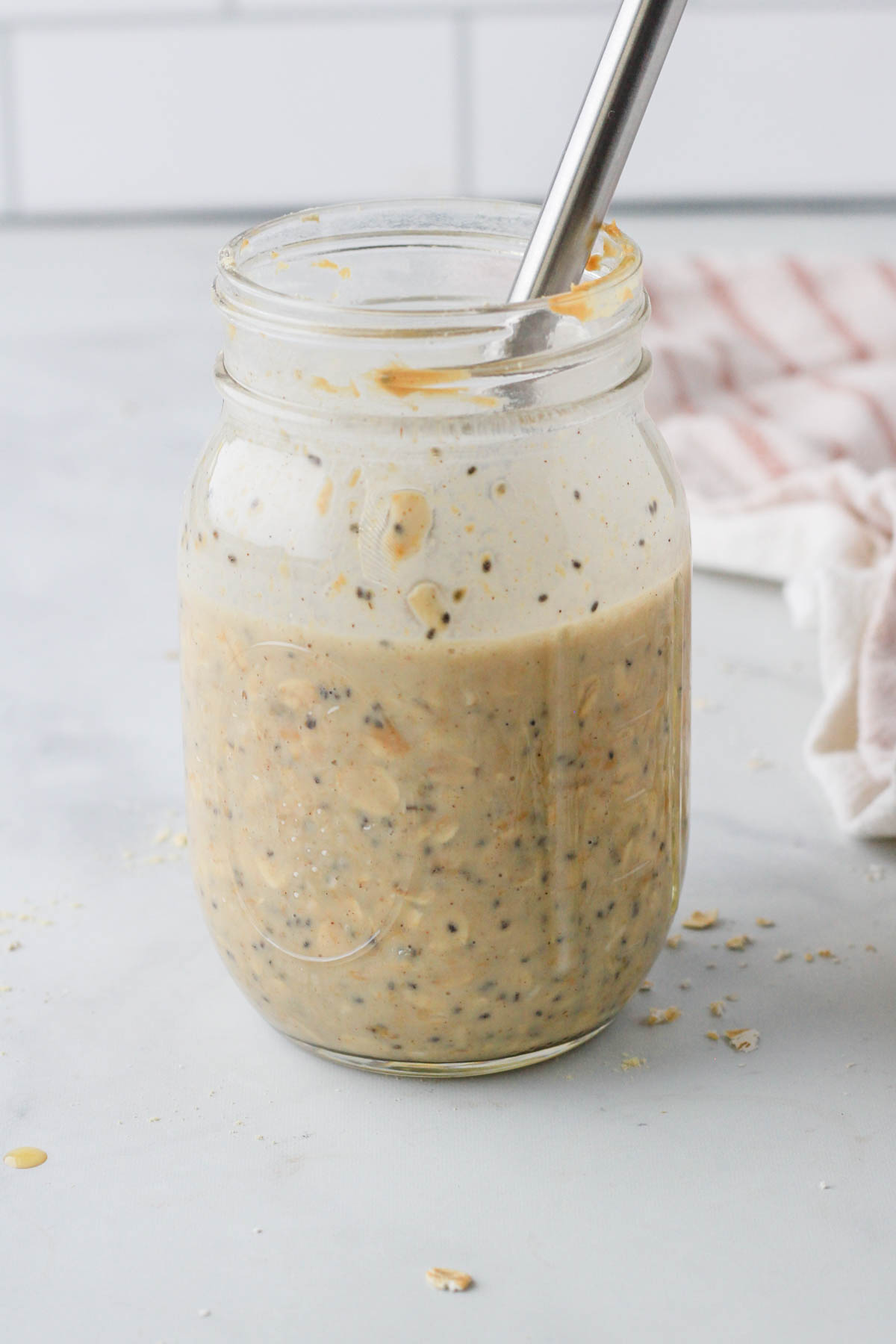 A small whisk mixing vegan vanilla peanut butter overnight oats in a glass mason jar.