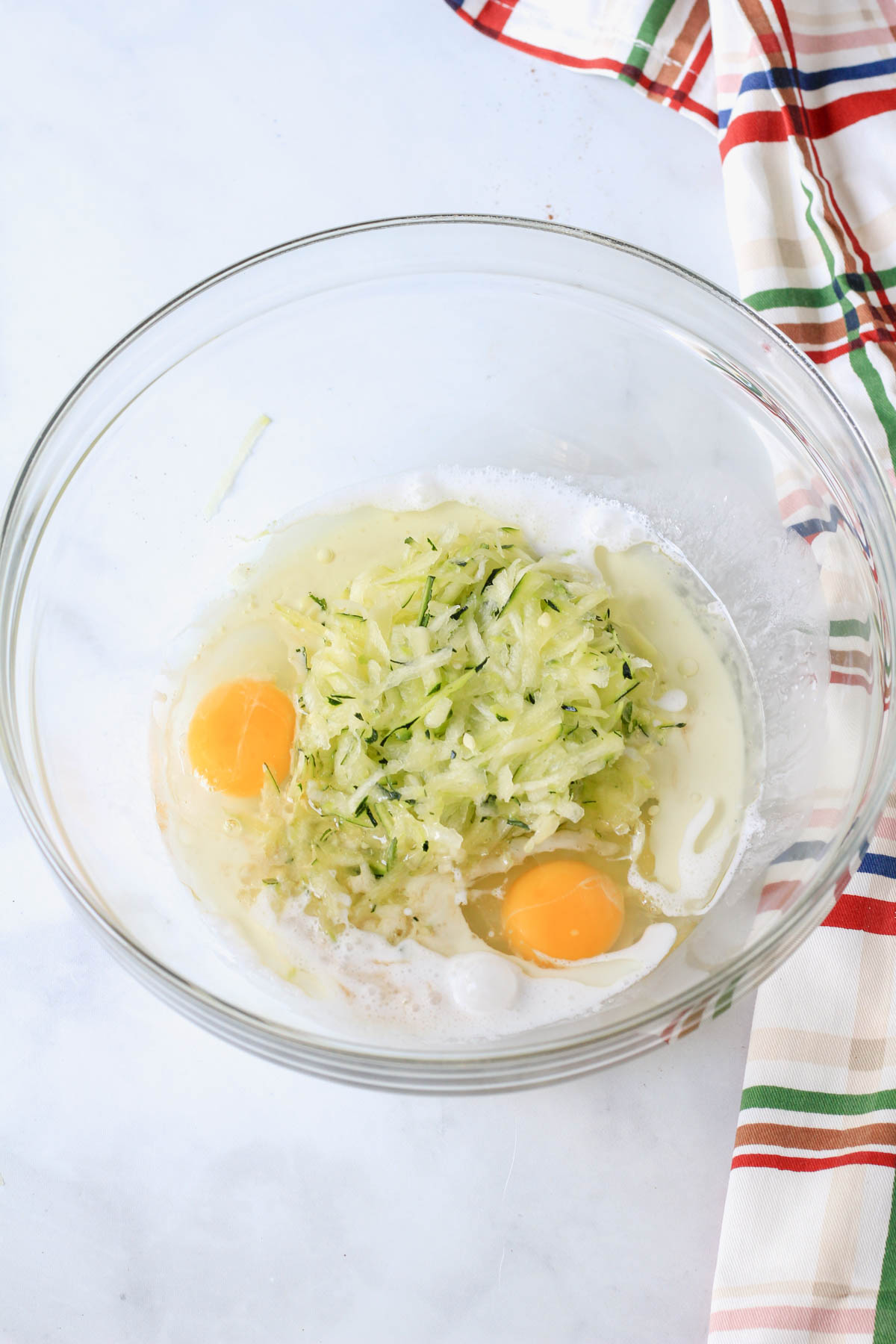 A glass mixing bowl with wet ingredients for dairy-free zucchini bread.