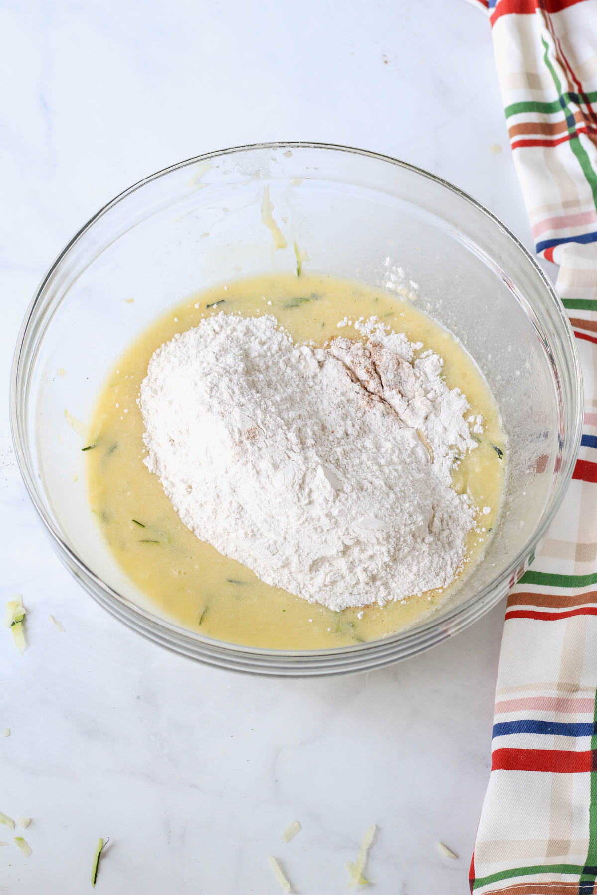 A glass mixing bowl with wet ingredients on the bottom and dry ingredients on top before mixing together.