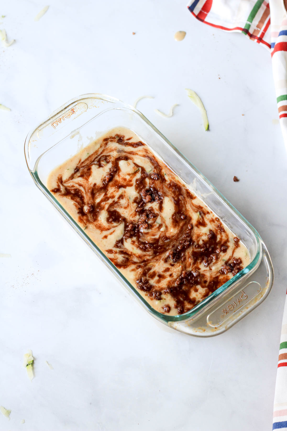 A glass baking pan with cinnamon swirl zucchini bread batter before baking.