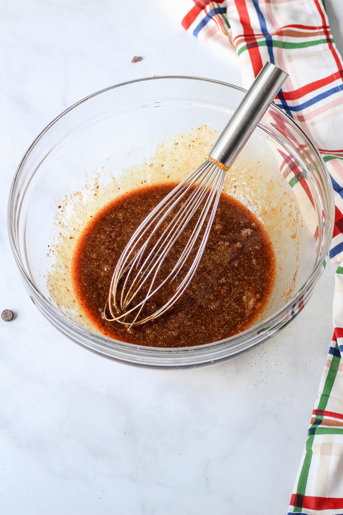 A glass bowl with the liquid ingredients for espresso chocolate chip cookie crust.