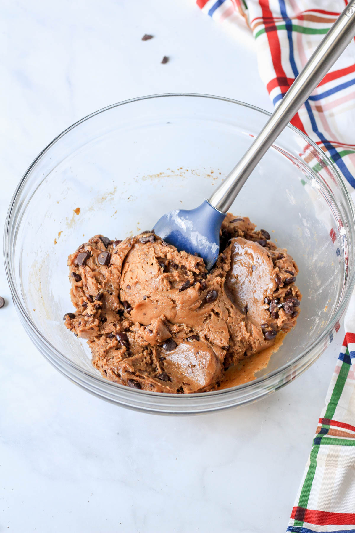 A blue spatula folding the chocolate chips into the espresso chocolate chip cookie crust.