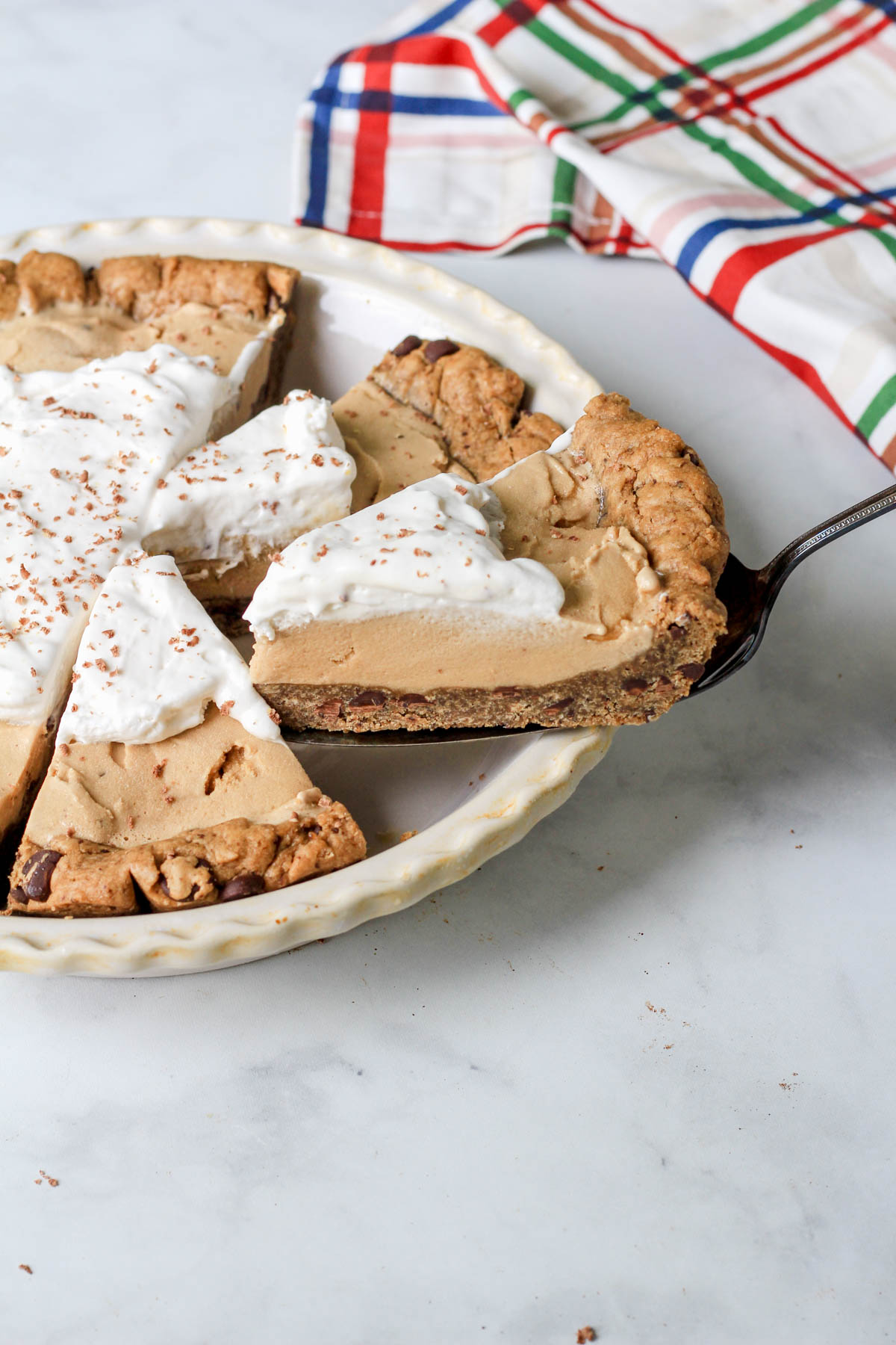 A pie pan with slices of dairy-free ice cream pie and a slice of coffee chip ice cream pie with espresso chocolate chip cookie crust on a pie server.