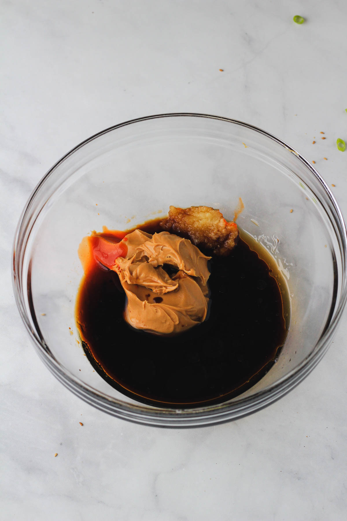 The ingredients for creamy peanut sauce in a glass bowl before mixing.