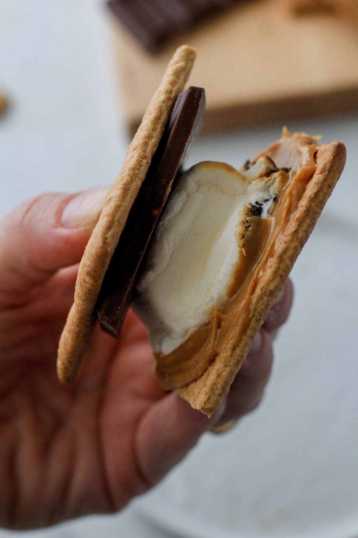 A hand holding a dairy-free s'more with peanut butter.