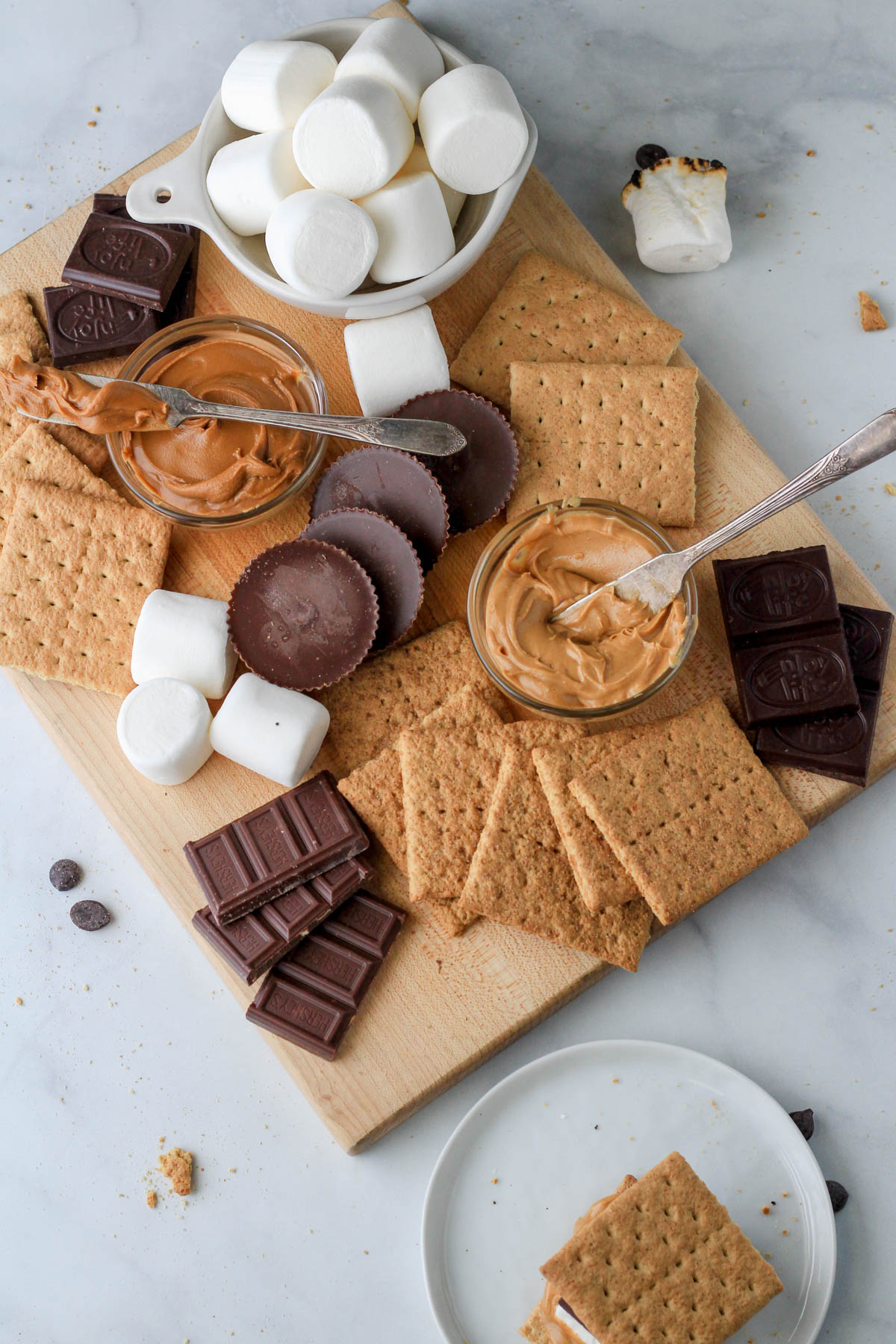 A dairy-free s'mores board with a small white plate and a s'more on top.