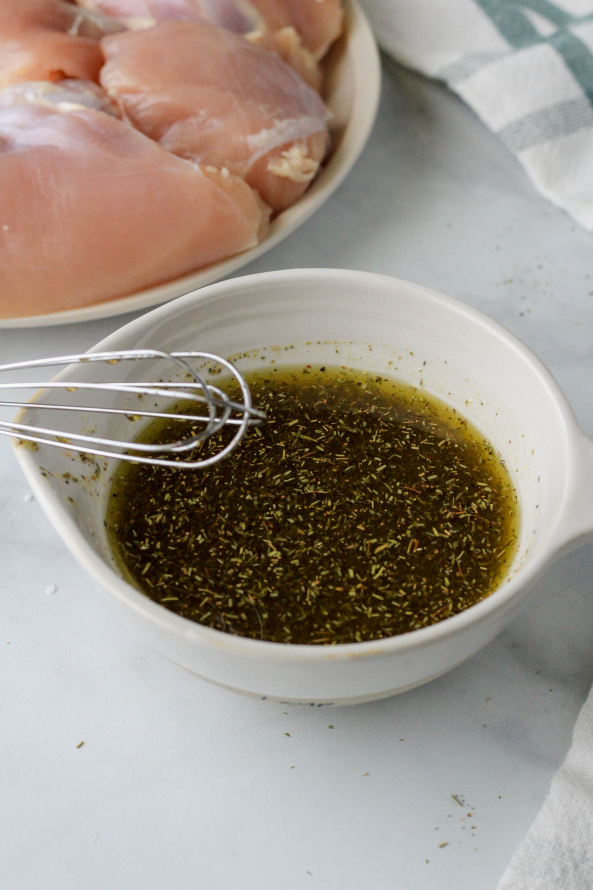 A small white bowl with the Italian marinade whisked together.