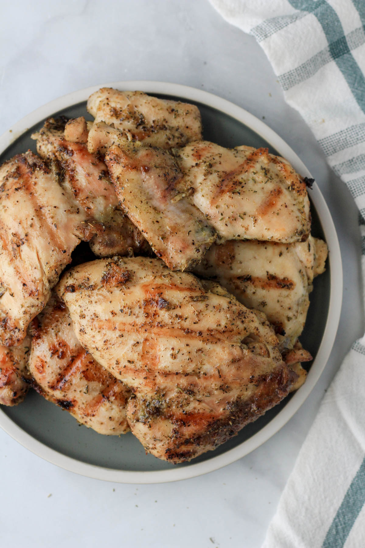 A top down photo of a green plate filled with grilled chicken thighs.