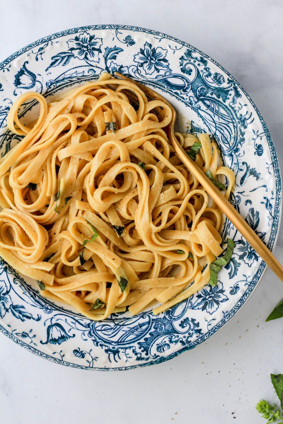 Simple vegan garlic one pot pasta in a white and blue bowl with a gold fork.