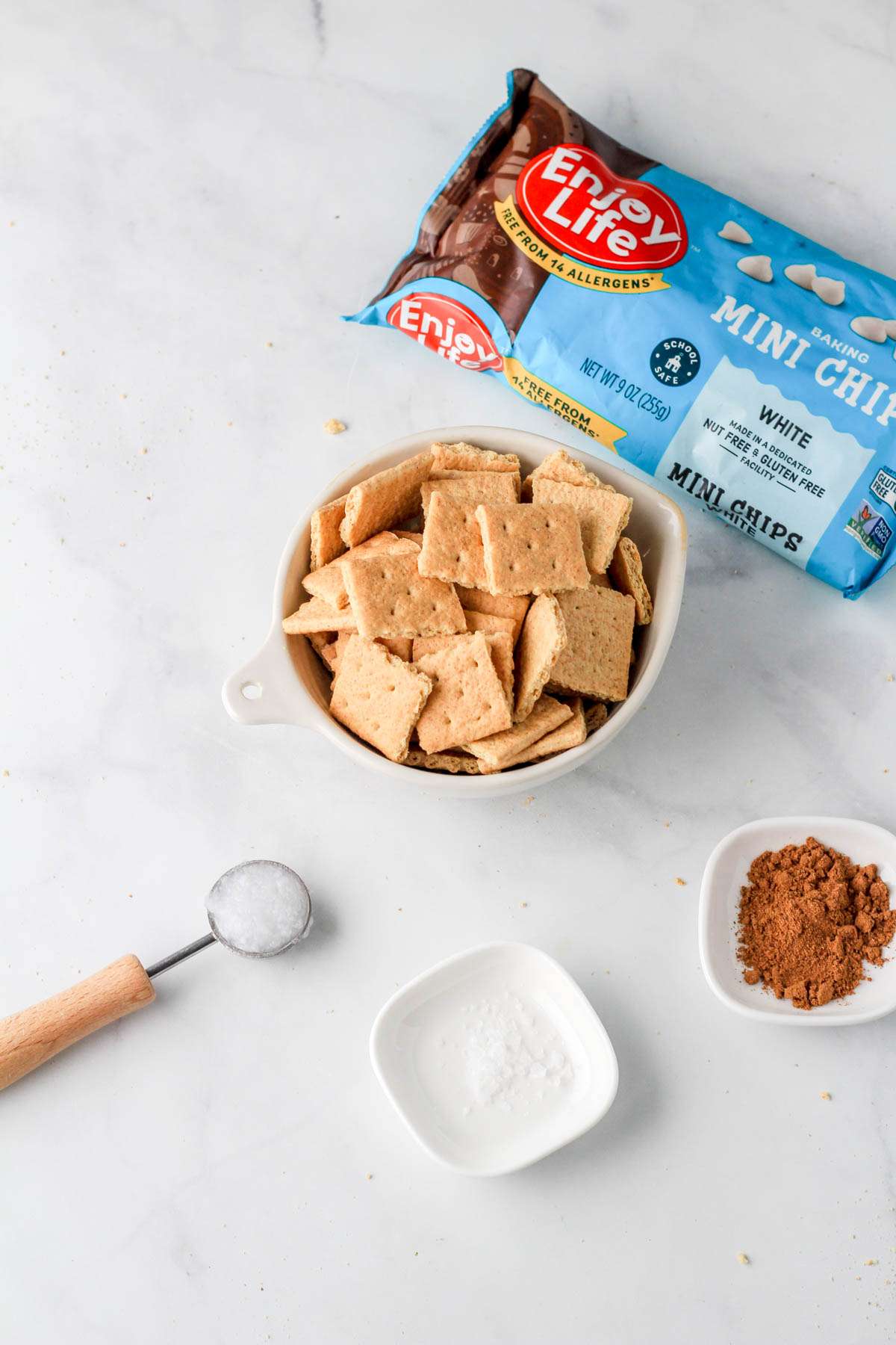 Ingredients for pumpkin spice white chocolate dipped graham crackers on a white counter.