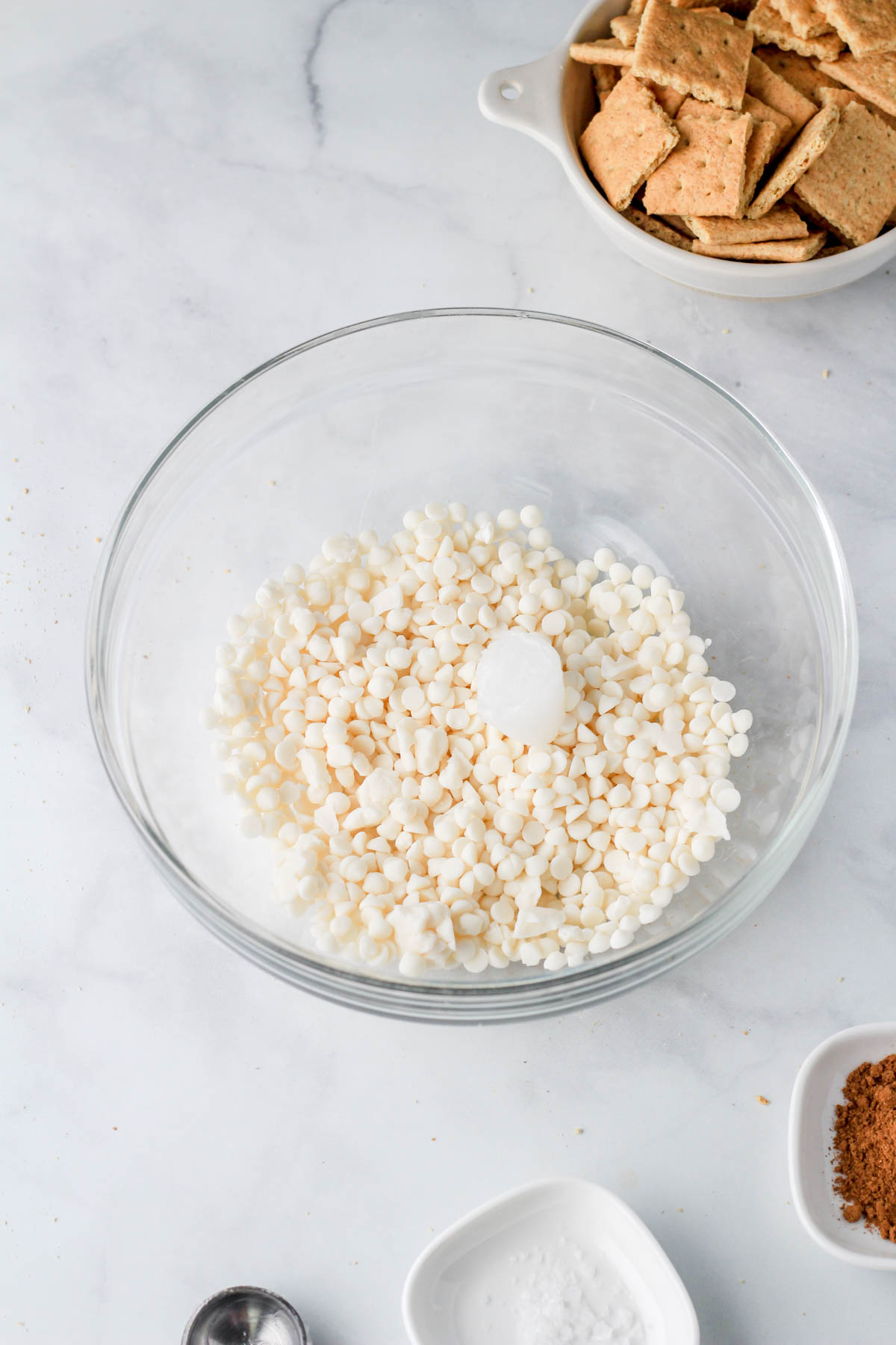 A large glass bowl with dairy-free white chocolate chips and coconut oil before melting.