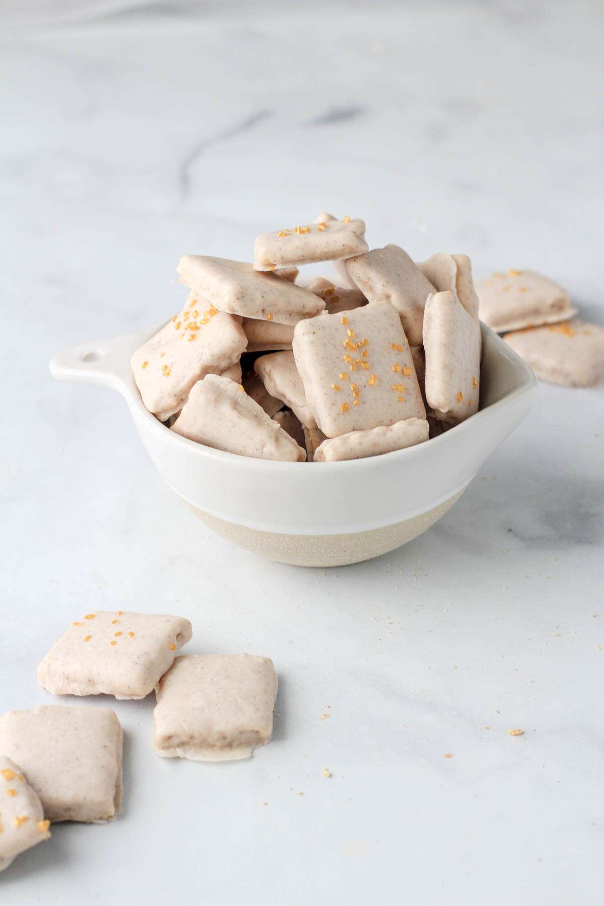 A small white bowl of pumpkin pie spice dipped graham crackers on a white counter.