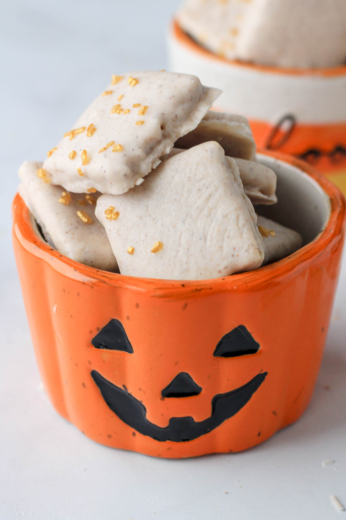 A small pumpkin decorated bowl filled with white chocolate pumpkin spice graham crackers.