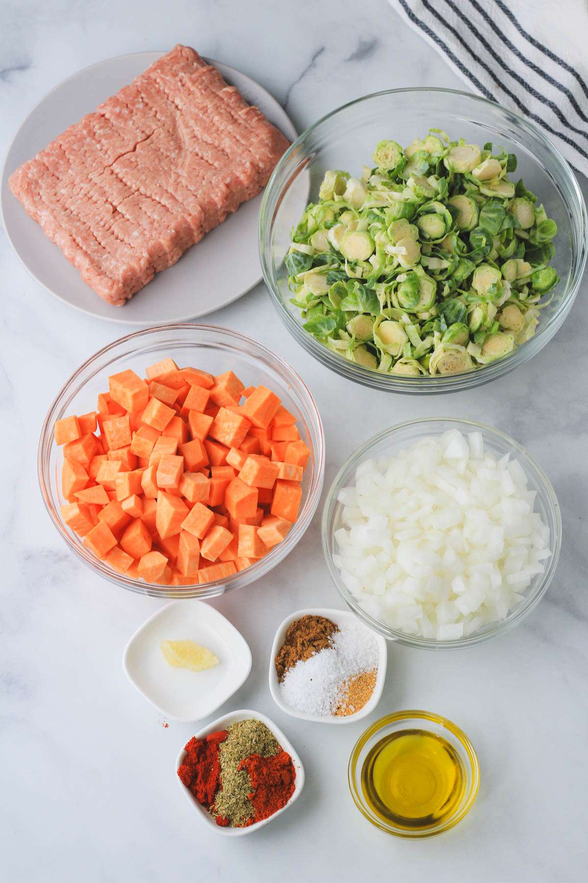 Ingredients for simple turkey taco skillet on a white counter with a blue and white striped dish towel.